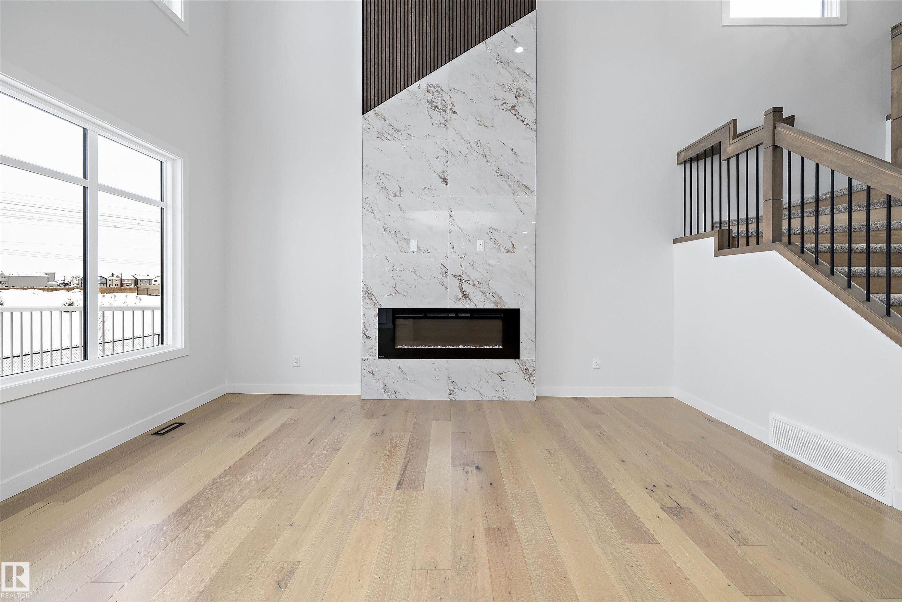 Unfurnished living room with a high ceiling, a high end fireplace, and light wood-style floors - 230 Edgemont Green Green Nw, Edmonton, AB - Indoor With Fireplace