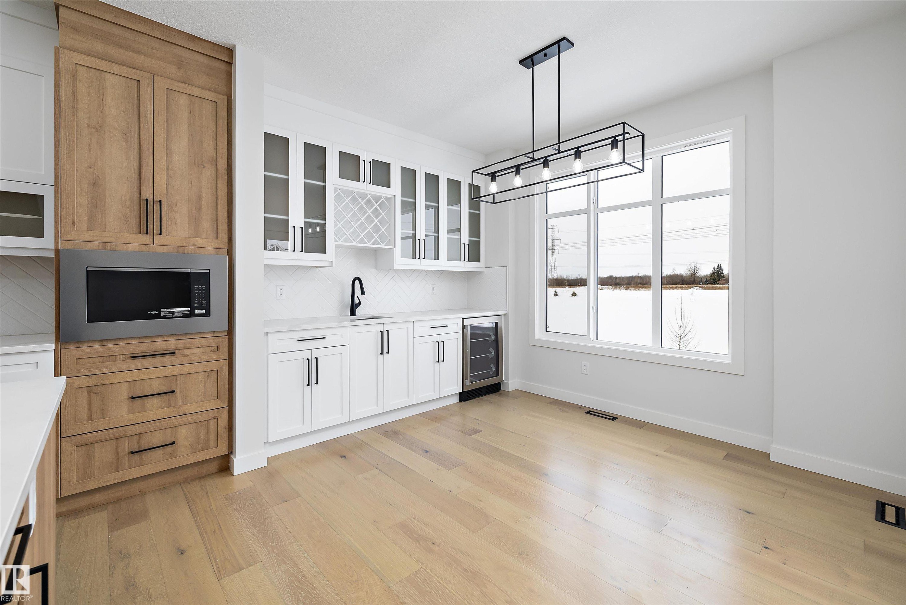 Kitchen with glass fronted cabinets, decorative light fixtures, two tone color scheme, wine cooler, and stainless steel microwave - 230 Edgemont Green Green Nw, Edmonton, AB - Indoor Photo Showing Kitchen