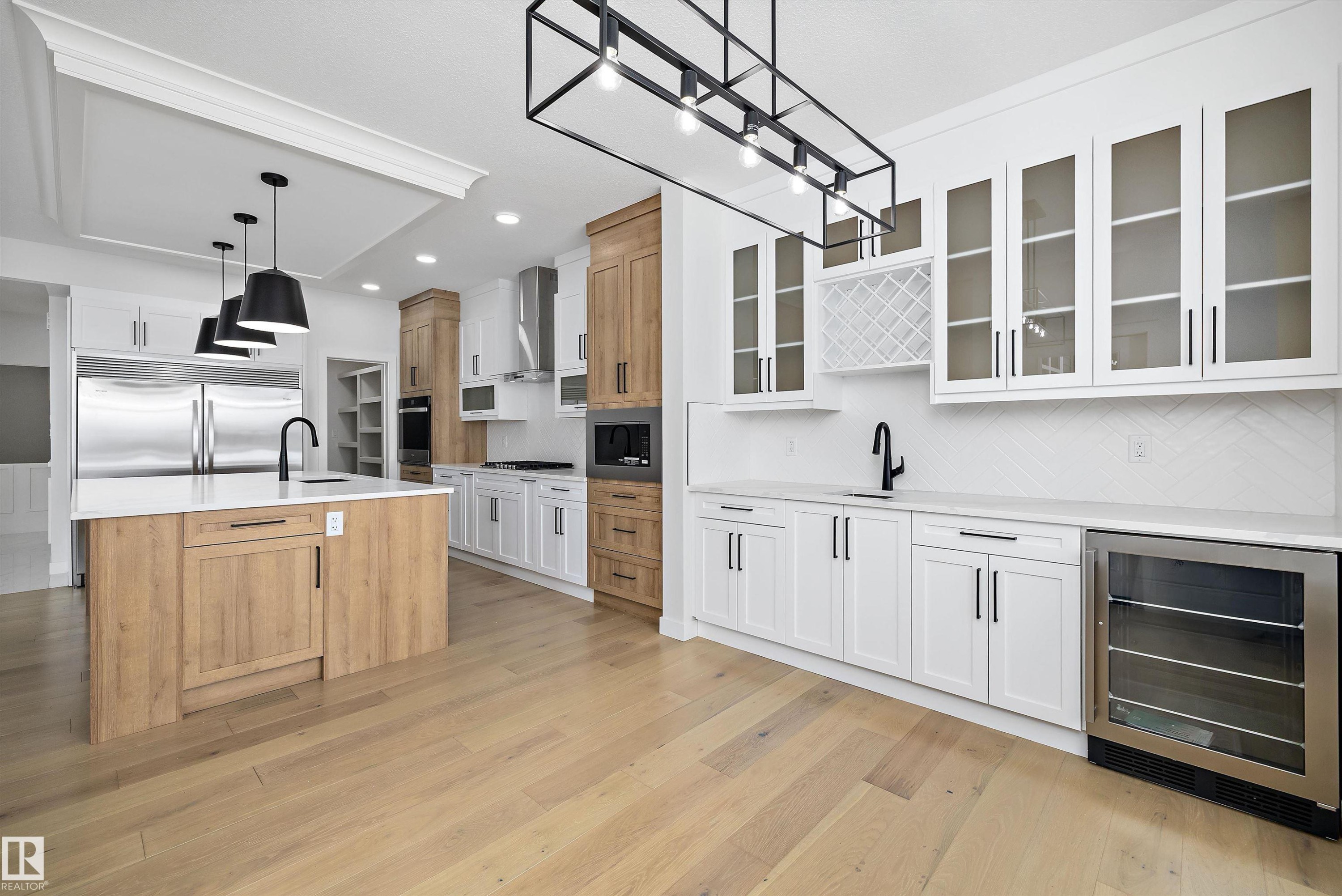 Two tone kitchen with two tone cabinets, wine cooler, pendant lighting, light stone counters, and light wood finished floors - 230 Edgemont Green Green Nw, Edmonton, AB - Indoor Photo Showing Kitchen With Upgraded Kitchen