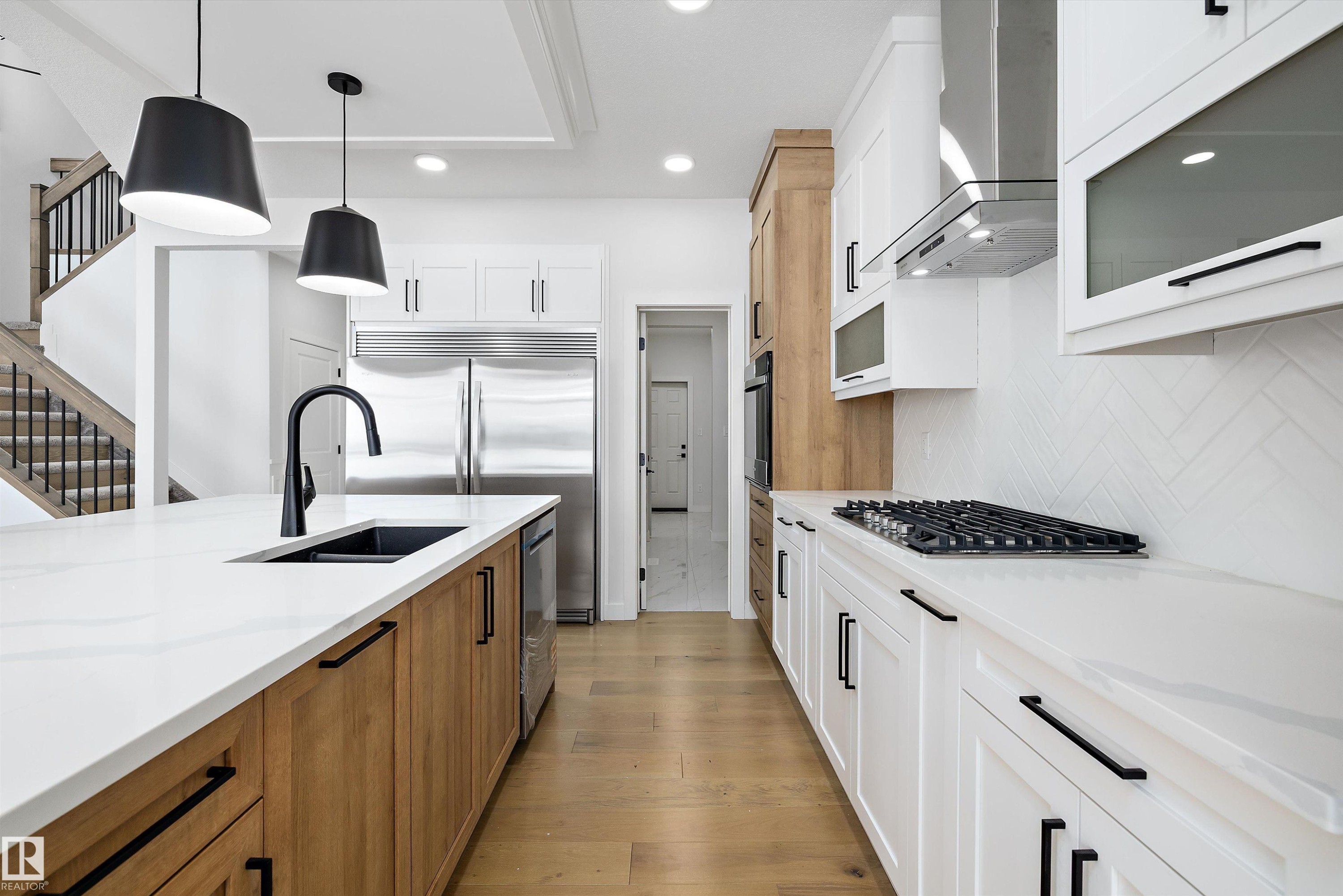 Kitchen with two tone cabinets, light wood-style flooring, pendant lighting, light stone counters, and stainless steel appliances - 230 Edgemont Green Green Nw, Edmonton, AB - Indoor Photo Showing Kitchen With Double Sink With Upgraded Kitchen