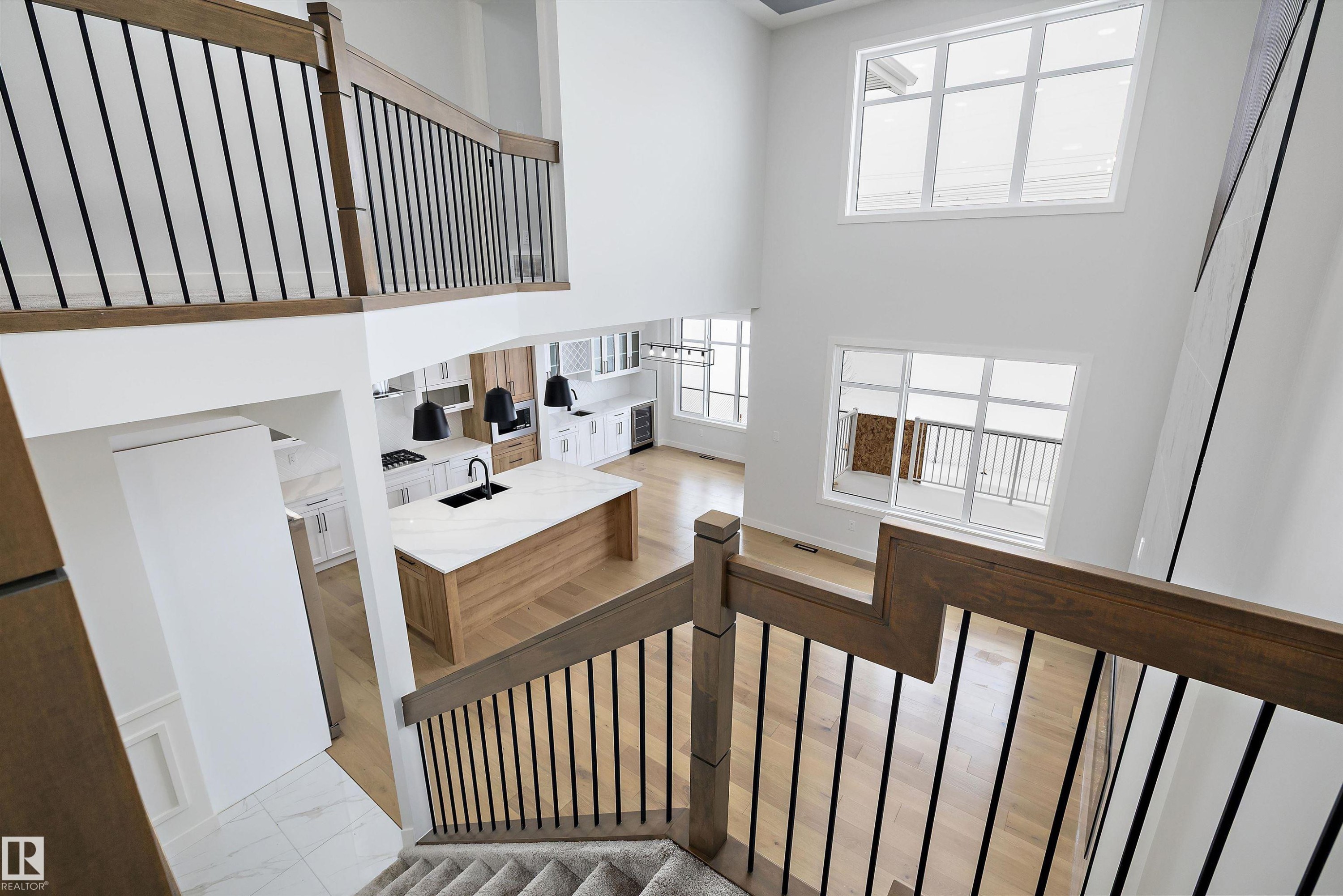 Staircase featuring a high ceiling, wood finished floors, and wine cooler - 230 Edgemont Green Green Nw, Edmonton, AB - Indoor Photo Showing Other Room