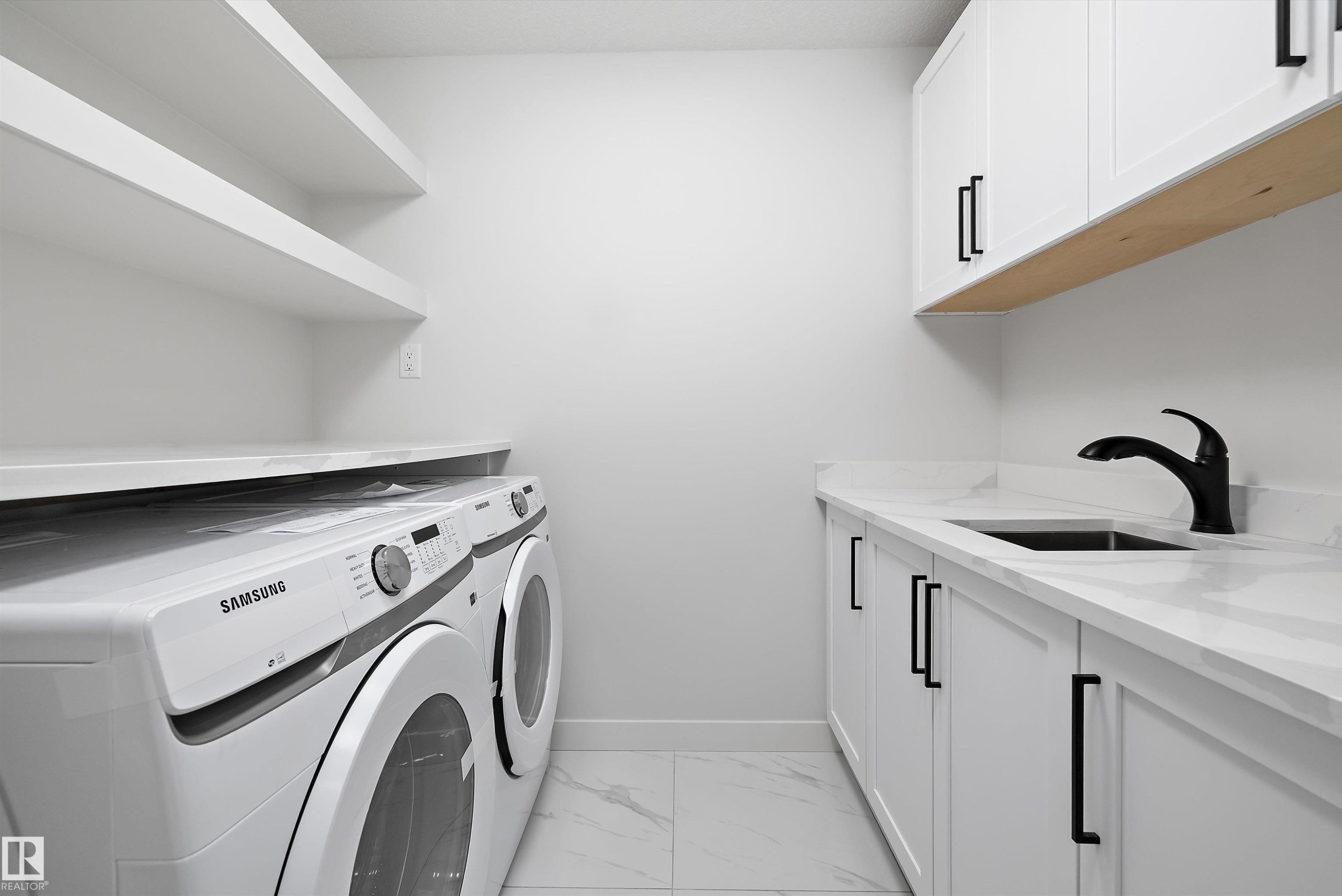 Laundry area featuring light marble finish floors, washing machine and dryer, and cabinet space - 230 Edgemont Green Green Nw, Edmonton, AB - Indoor Photo Showing Laundry Room