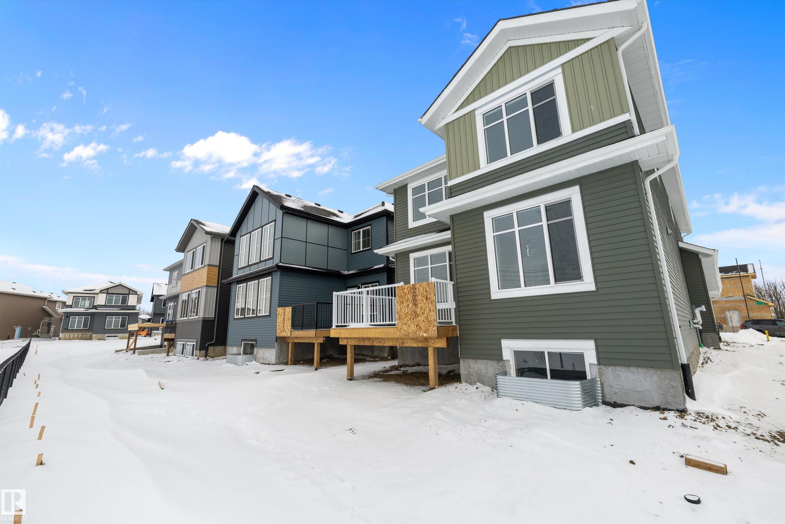 Snow covered house with board and batten siding, a wooden deck, and a residential view - 230 Edgemont Green Green Nw, Edmonton, AB - Outdoor