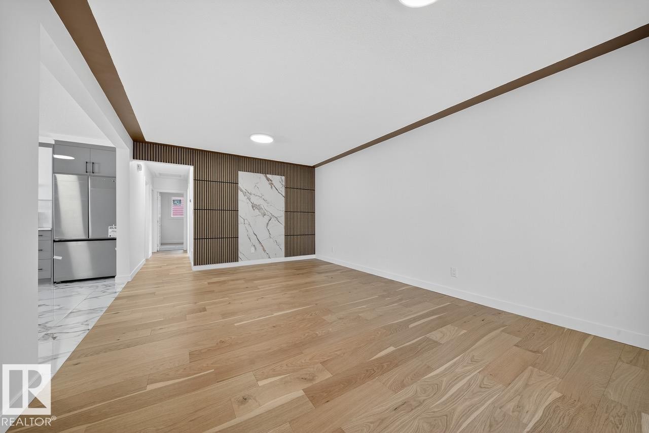 Unfurnished living room featuring light wood-style flooring and an accent wall - 12919 113A Street, Edmonton, AB - Indoor Photo Showing Other Room