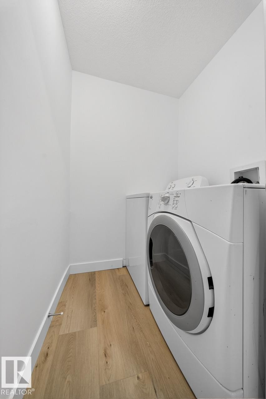 Laundry area with wood finished floors, a textured ceiling, and independent washer and dryer - 12919 113A Street, Edmonton, AB - Indoor Photo Showing Laundry Room