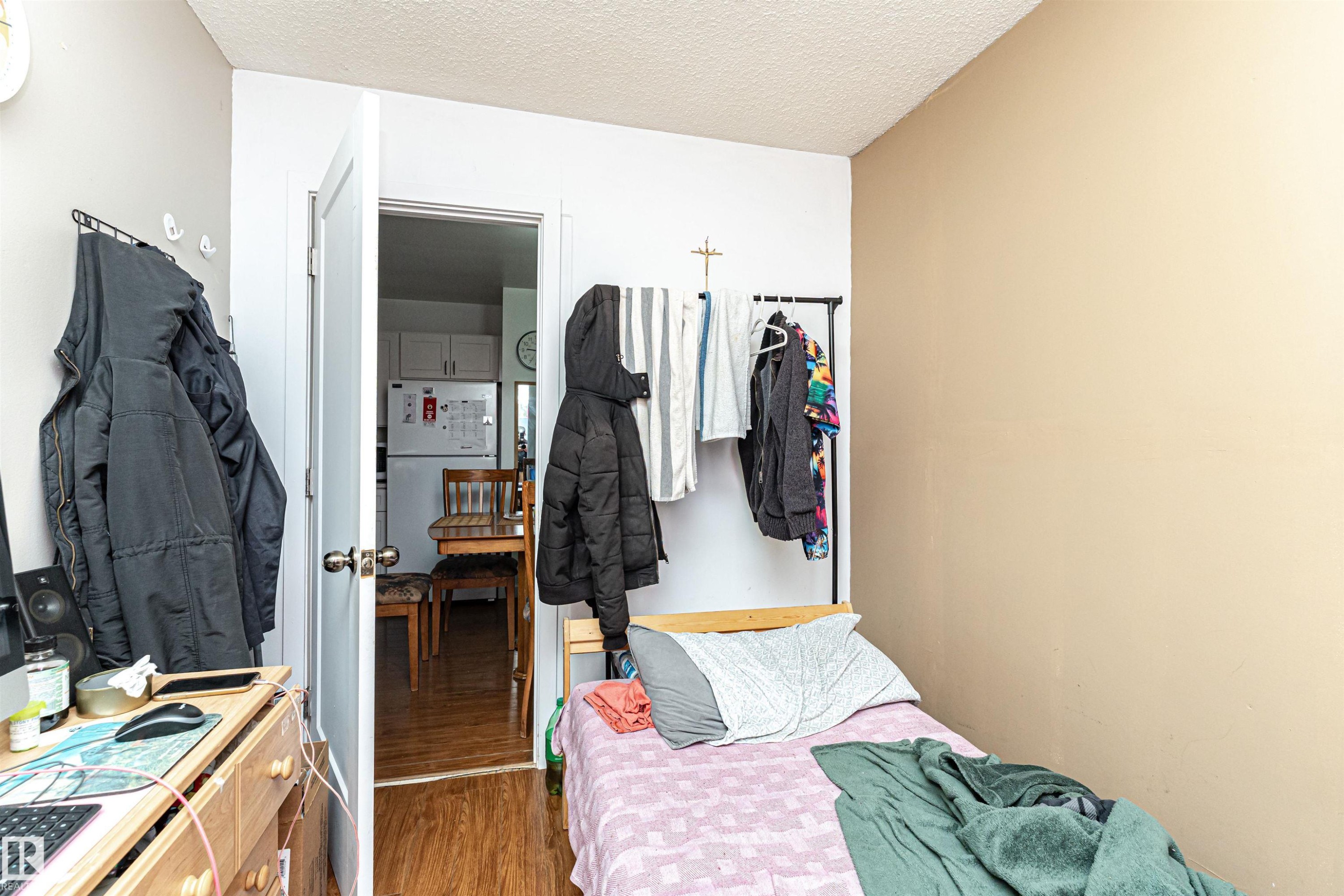 Bedroom with freestanding refrigerator, a textured ceiling, wood finished floors, a closet, and an office area - 2349 Millbourne Road W, Edmonton, AB - Indoor Photo Showing Bedroom