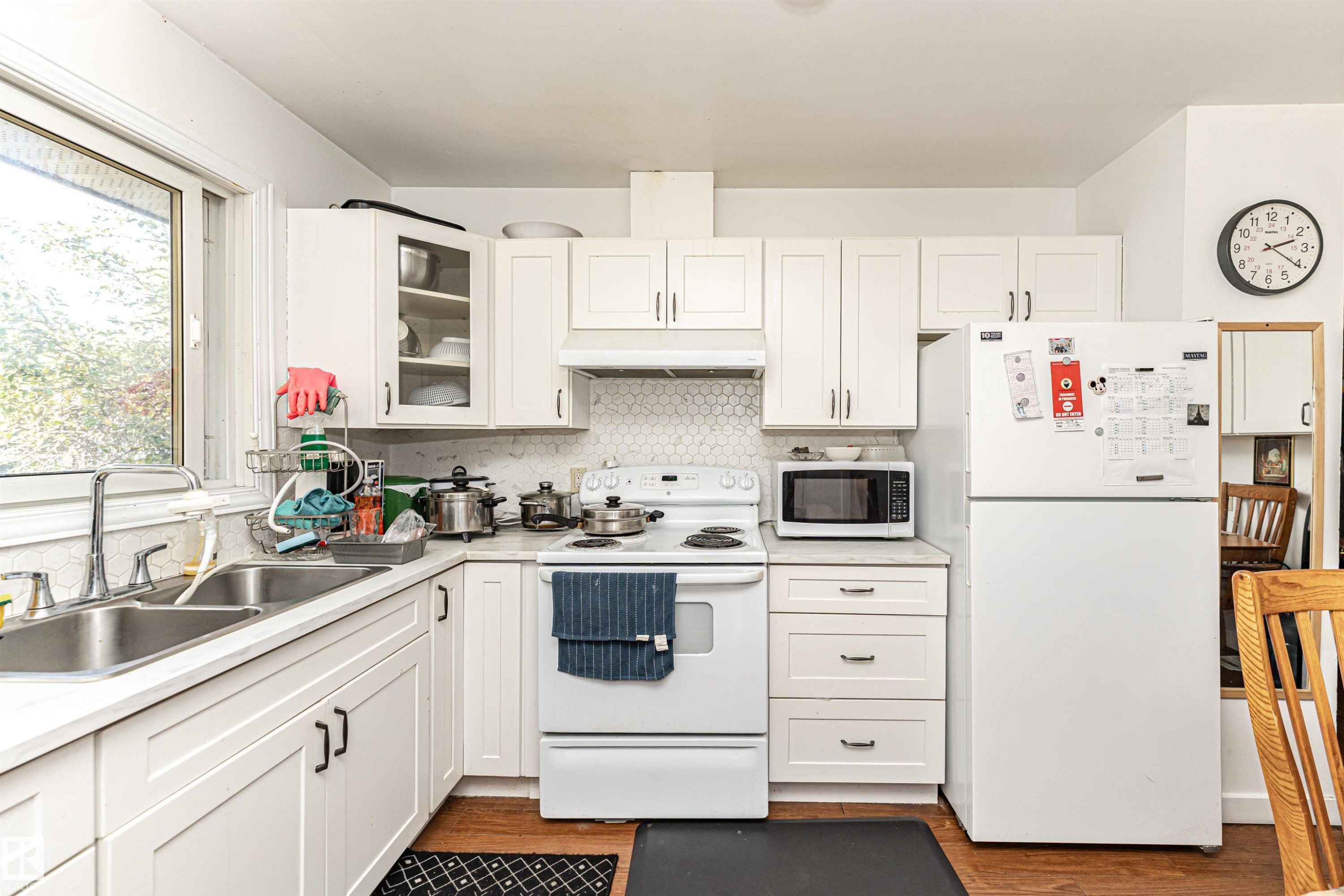 Kitchen with white appliances, white cabinetry, light countertops, and under cabinet range hood - 2349 Millbourne Road W, Edmonton, AB - Indoor Photo Showing Kitchen With Double Sink