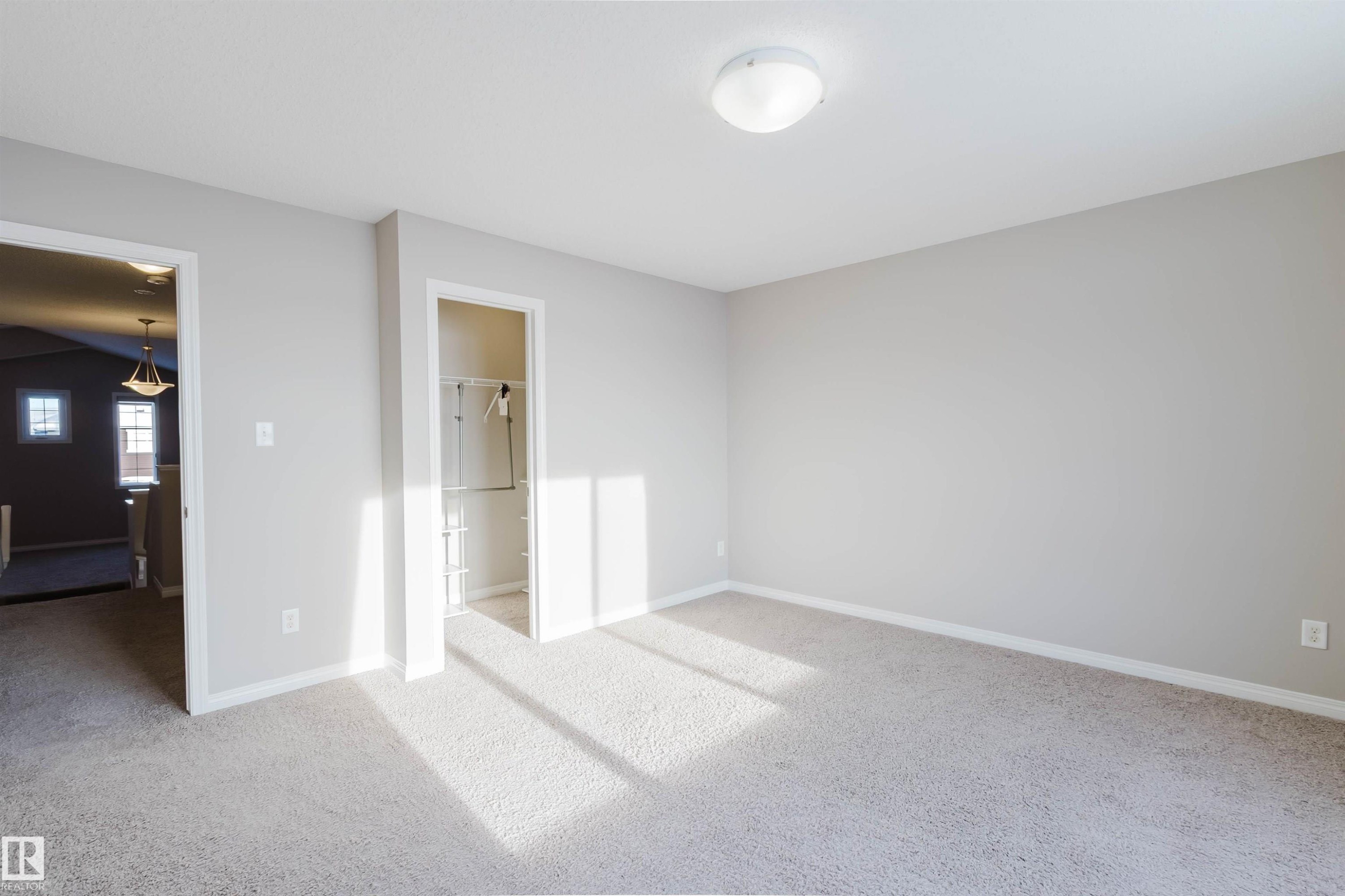 Unfurnished bedroom with light carpet and a walk in closet - 16627 18 Avenue, Edmonton, AB - Indoor Photo Showing Other Room