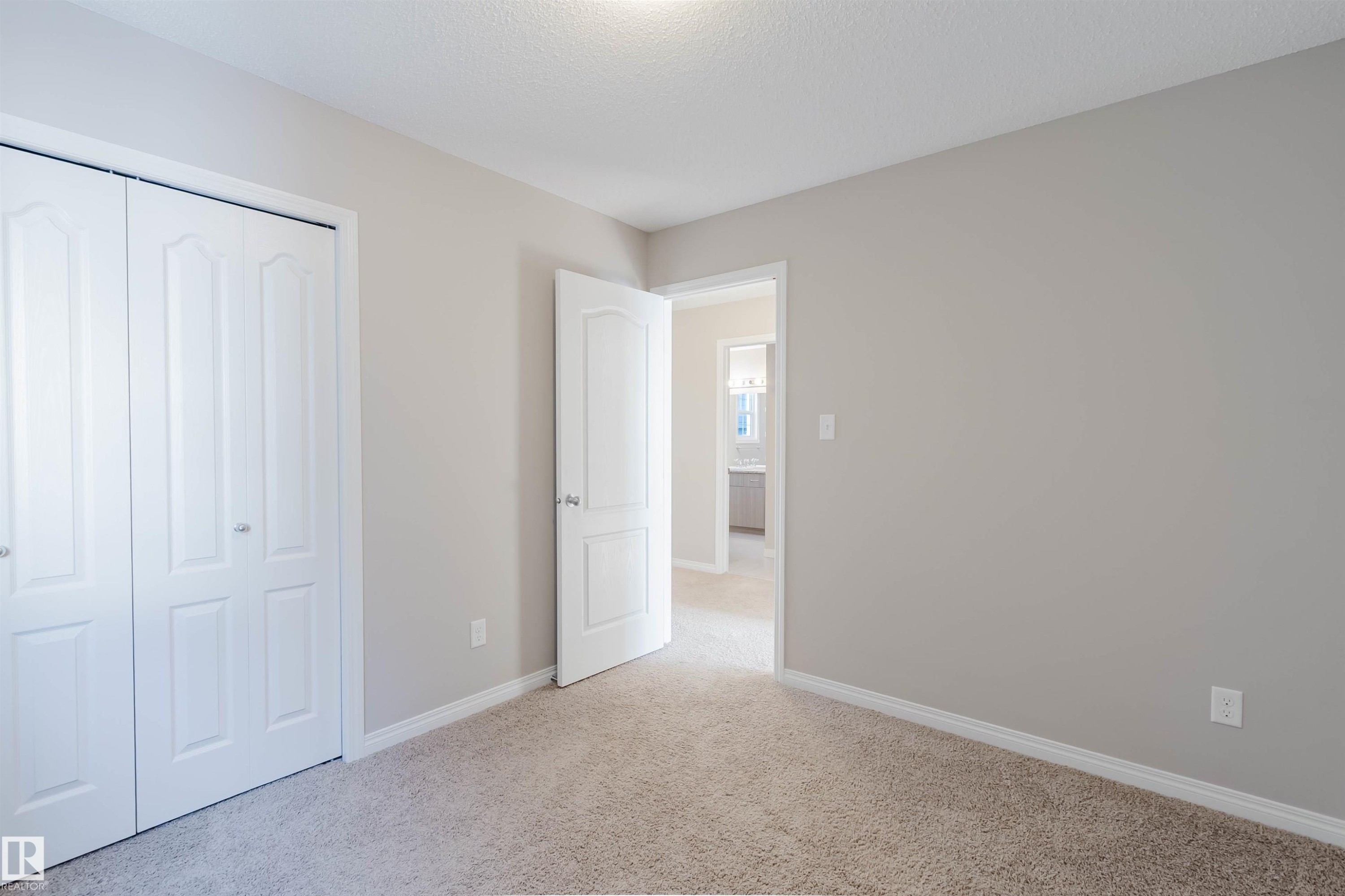 Unfurnished bedroom with light carpet, a closet, and a textured ceiling - 16627 18 Avenue, Edmonton, AB - Indoor