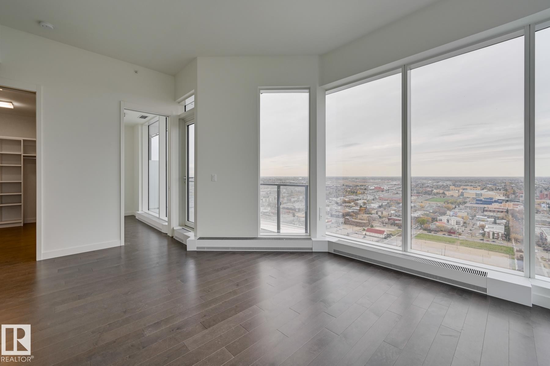 Empty room featuring baseboard heating and dark wood-style floors - 2303 10360 102 Street, Edmonton, AB - Indoor