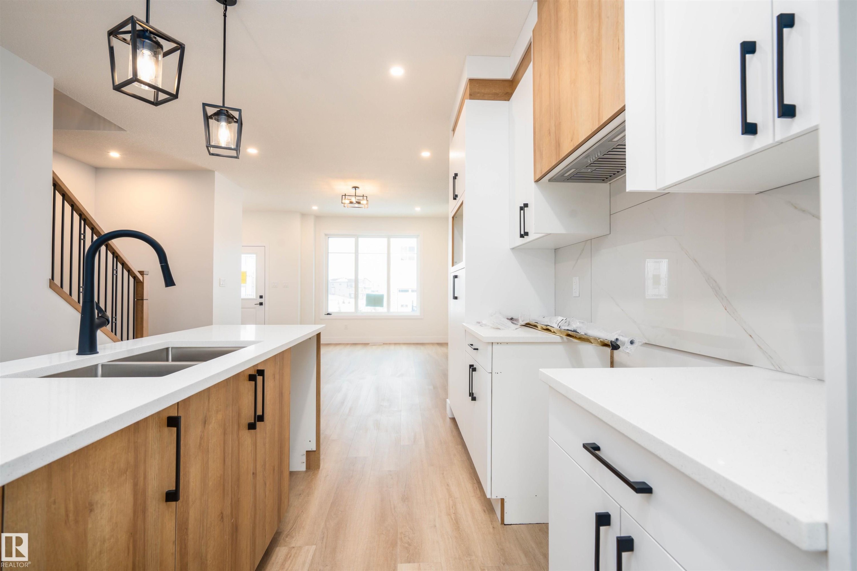 Kitchen featuring white cabinets, light wood-style flooring, light stone counters, modern cabinets, and brown cabinets - 430 Crystal Creek Link, Leduc, AB - Indoor Photo Showing Kitchen With Double Sink With Upgraded Kitchen