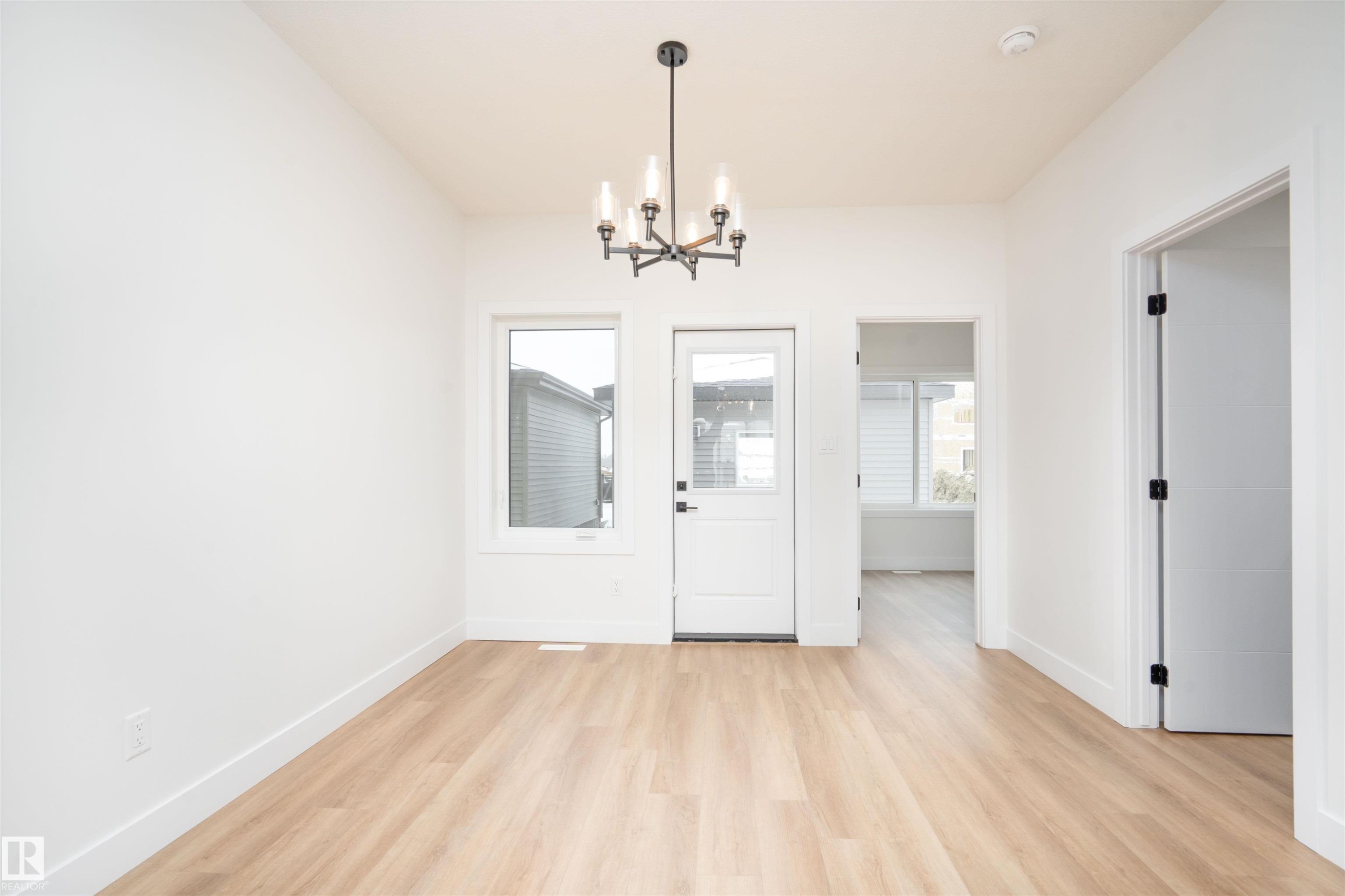 Unfurnished dining area with light wood-style flooring, a chandelier, and plenty of natural light - 430 Crystal Creek Link, Leduc, AB - Indoor Photo Showing Other Room