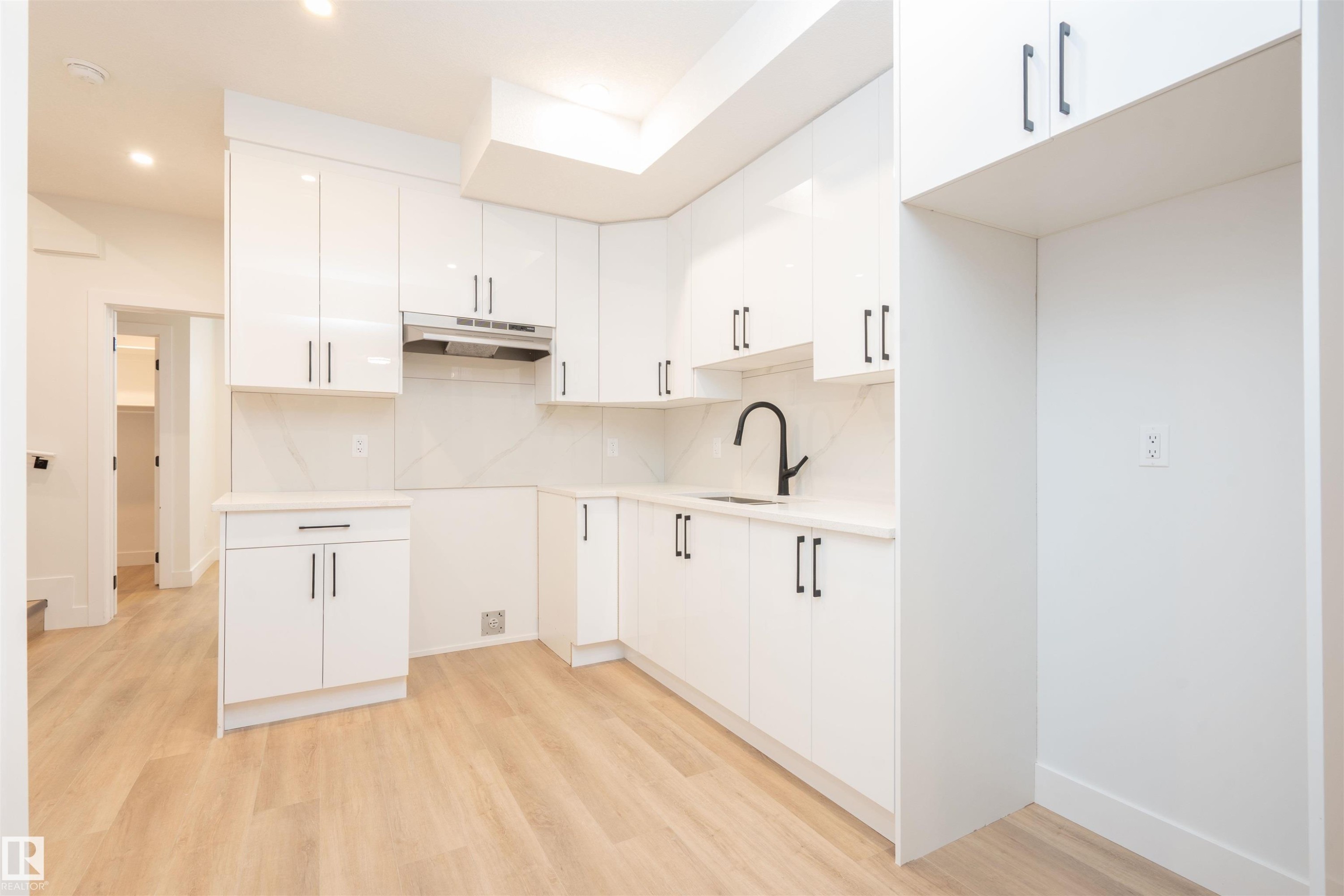 Kitchen featuring white cabinetry, light wood-style flooring, under cabinet range hood, modern cabinets, and recessed lighting - 430 Crystal Creek Link, Leduc, AB - Indoor Photo Showing Kitchen