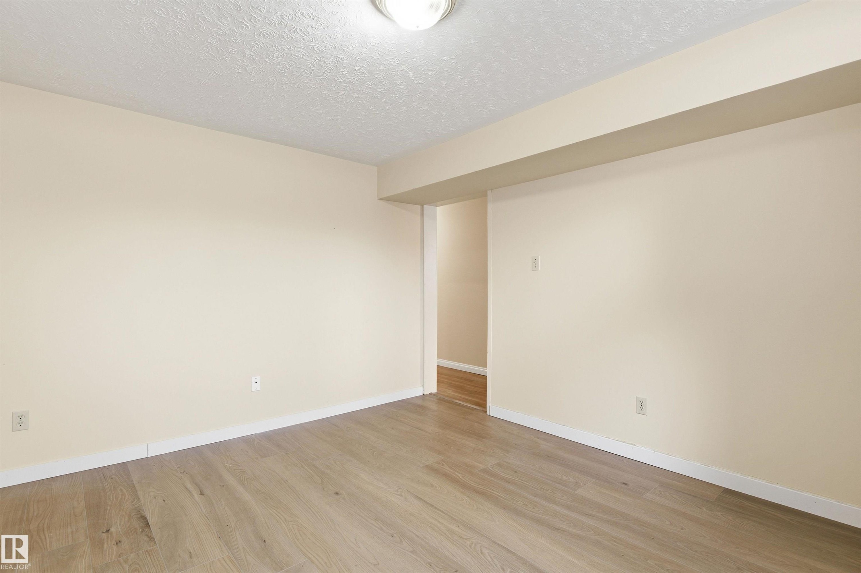 Unfurnished room featuring light wood-style floors and a textured ceiling - 10332 82 Street, Edmonton, AB - Indoor Photo Showing Other Room