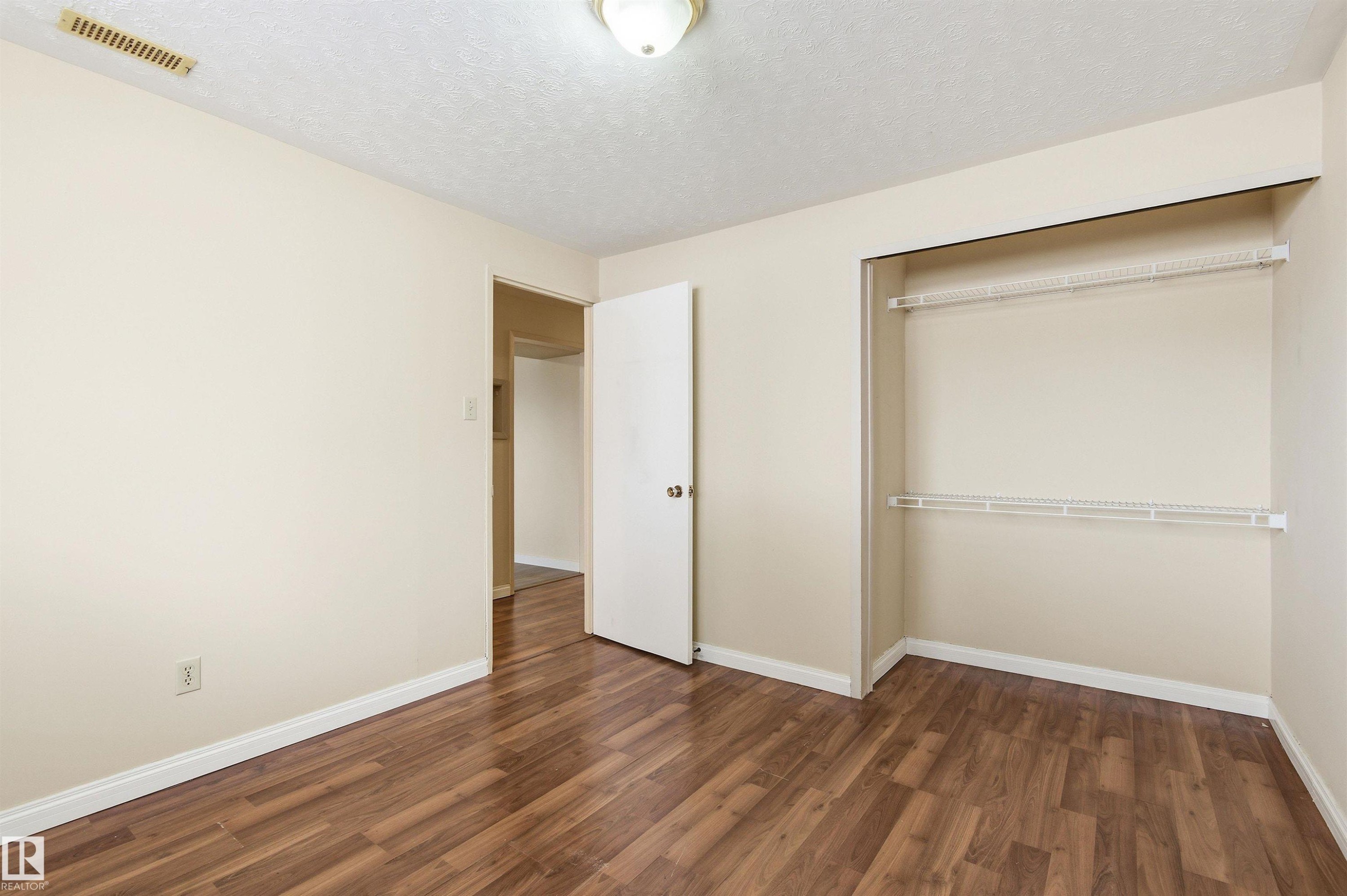 Unfurnished bedroom featuring a textured ceiling, dark wood-style floors, and a closet - 10332 82 Street, Edmonton, AB - Indoor Photo Showing Other Room