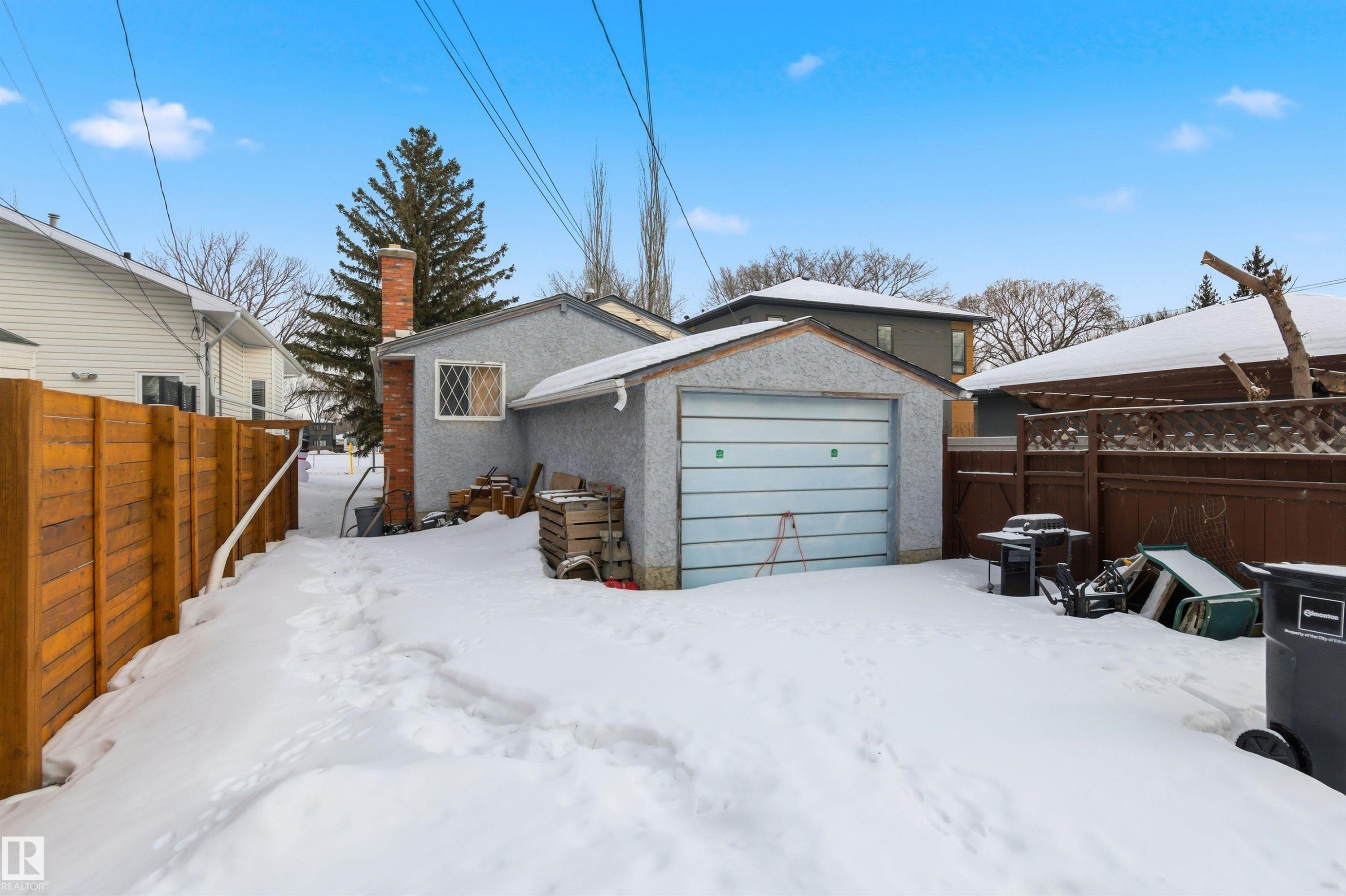 Snow covered rear of property with an outbuilding, a chimney, and stucco siding - 10332 82 Street, Edmonton, AB - Outdoor
