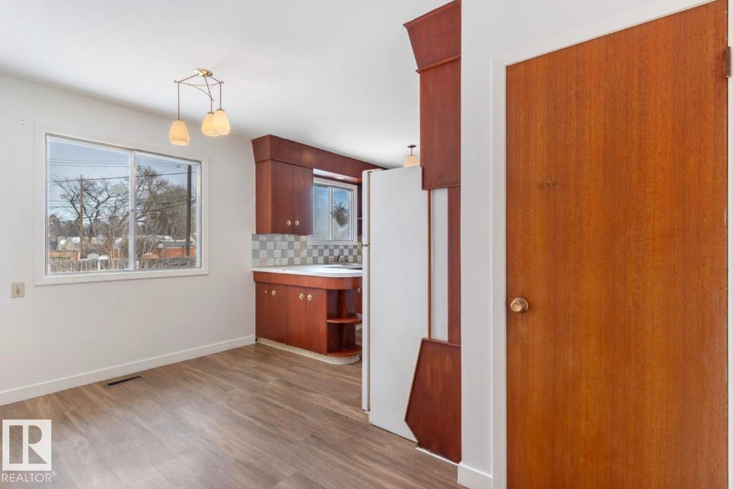 Kitchen with light countertops, freestanding refrigerator, light wood-style floors, backsplash, and decorative light fixtures - 3810 110 Avenue, Edmonton, AB - Indoor Photo Showing Other Room