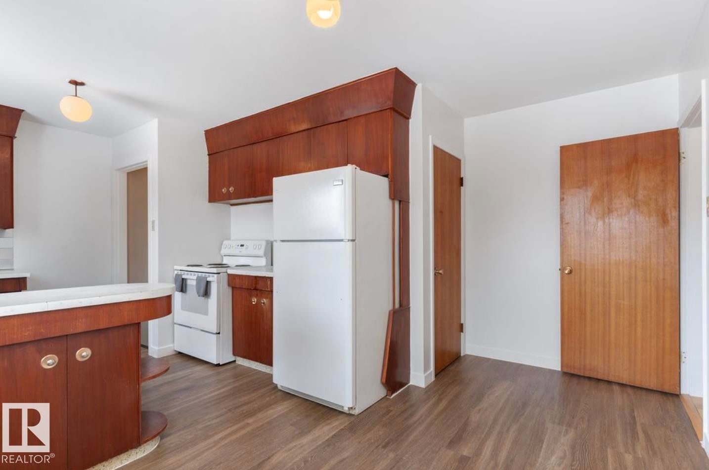 Kitchen featuring light countertops, white appliances, dark wood finished floors, decorative light fixtures, and brown cabinetry - 3810 110 Avenue, Edmonton, AB - Indoor Photo Showing Kitchen