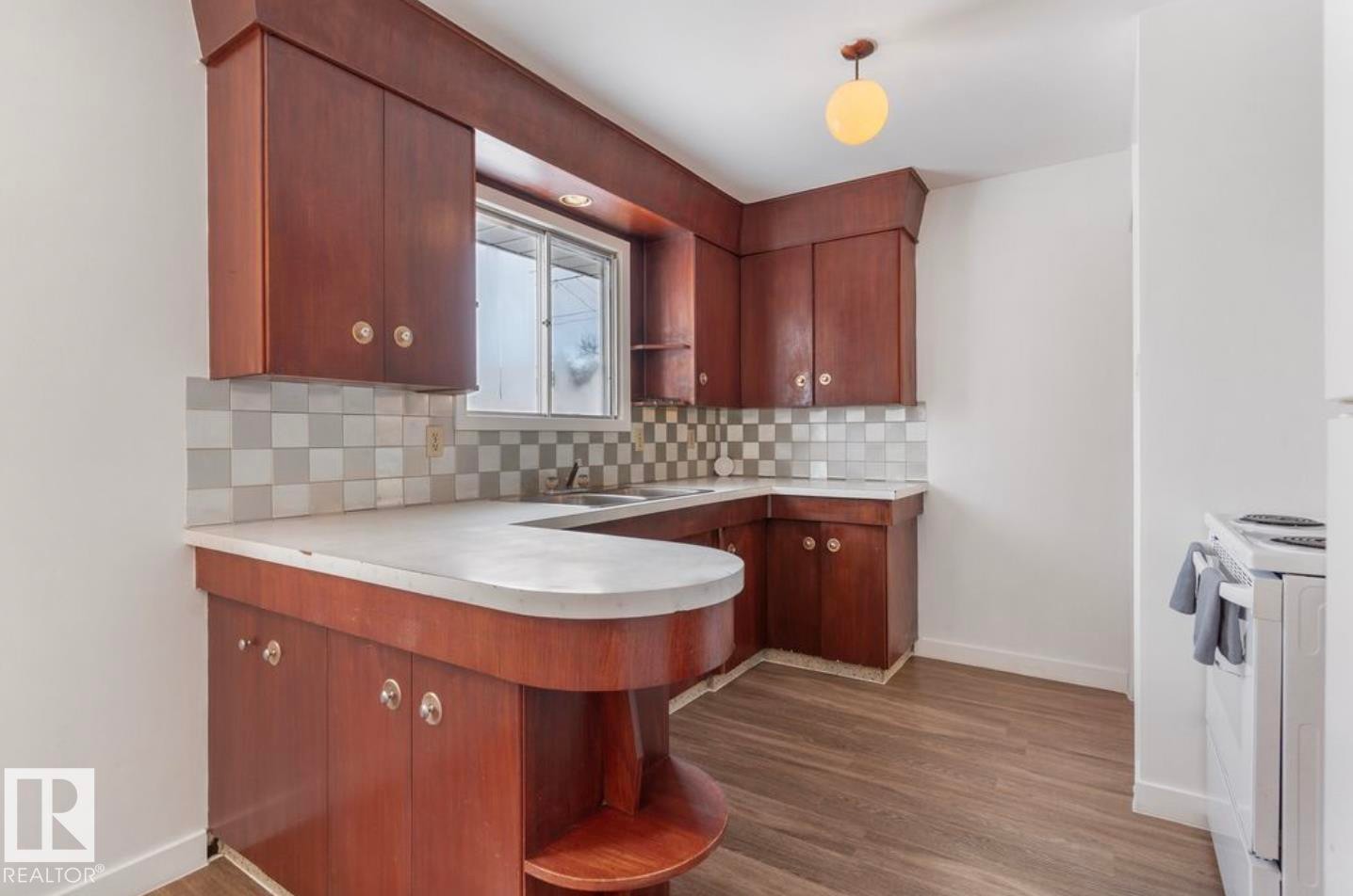 Kitchen with a peninsula, light countertops, white range with electric stovetop, dark wood finished floors, and decorative backsplash - 3810 110 Avenue, Edmonton, AB - Indoor Photo Showing Kitchen