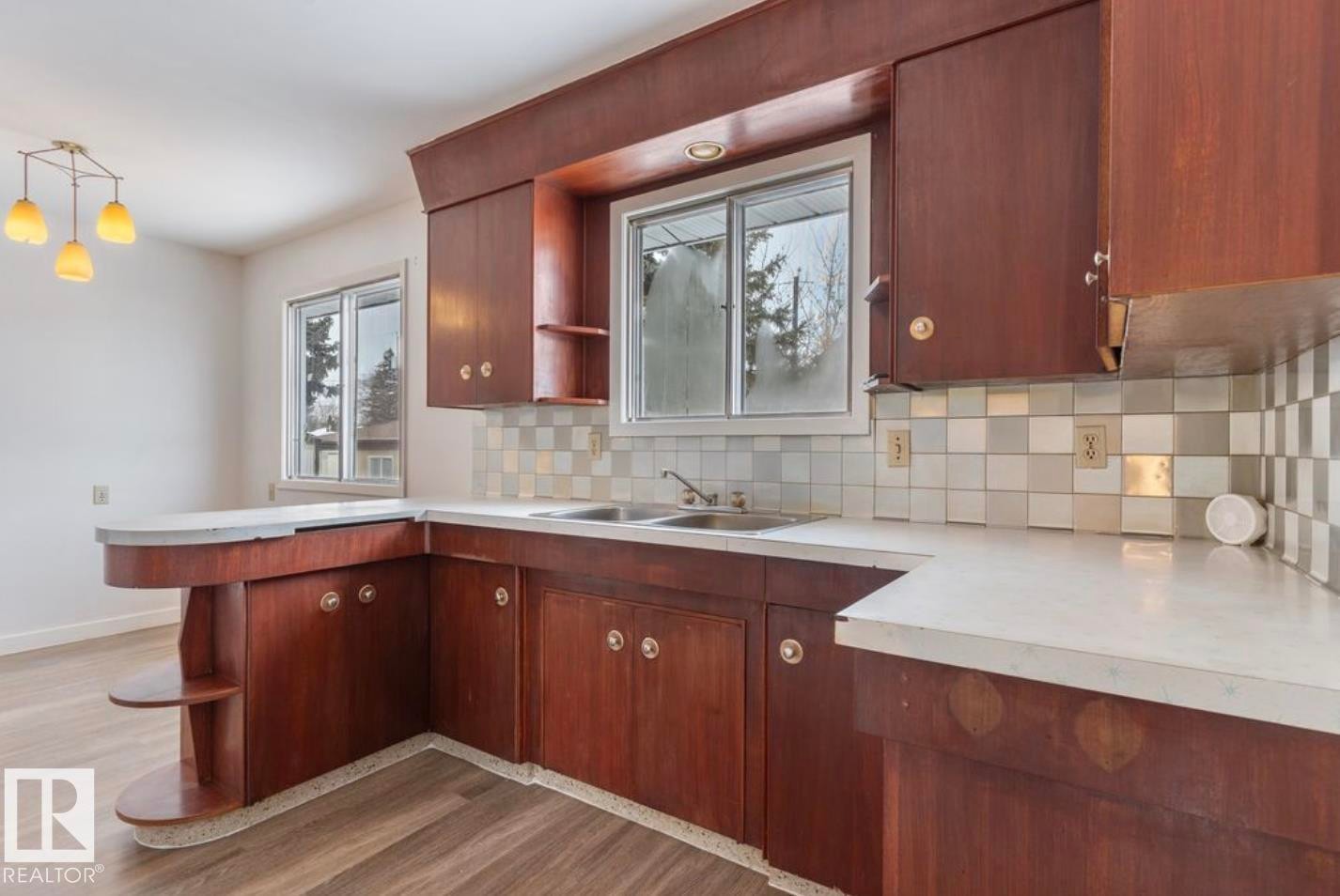 Kitchen featuring open shelves, light countertops, decorative backsplash, and a peninsula - 3810 110 Avenue, Edmonton, AB - Indoor Photo Showing Kitchen With Double Sink