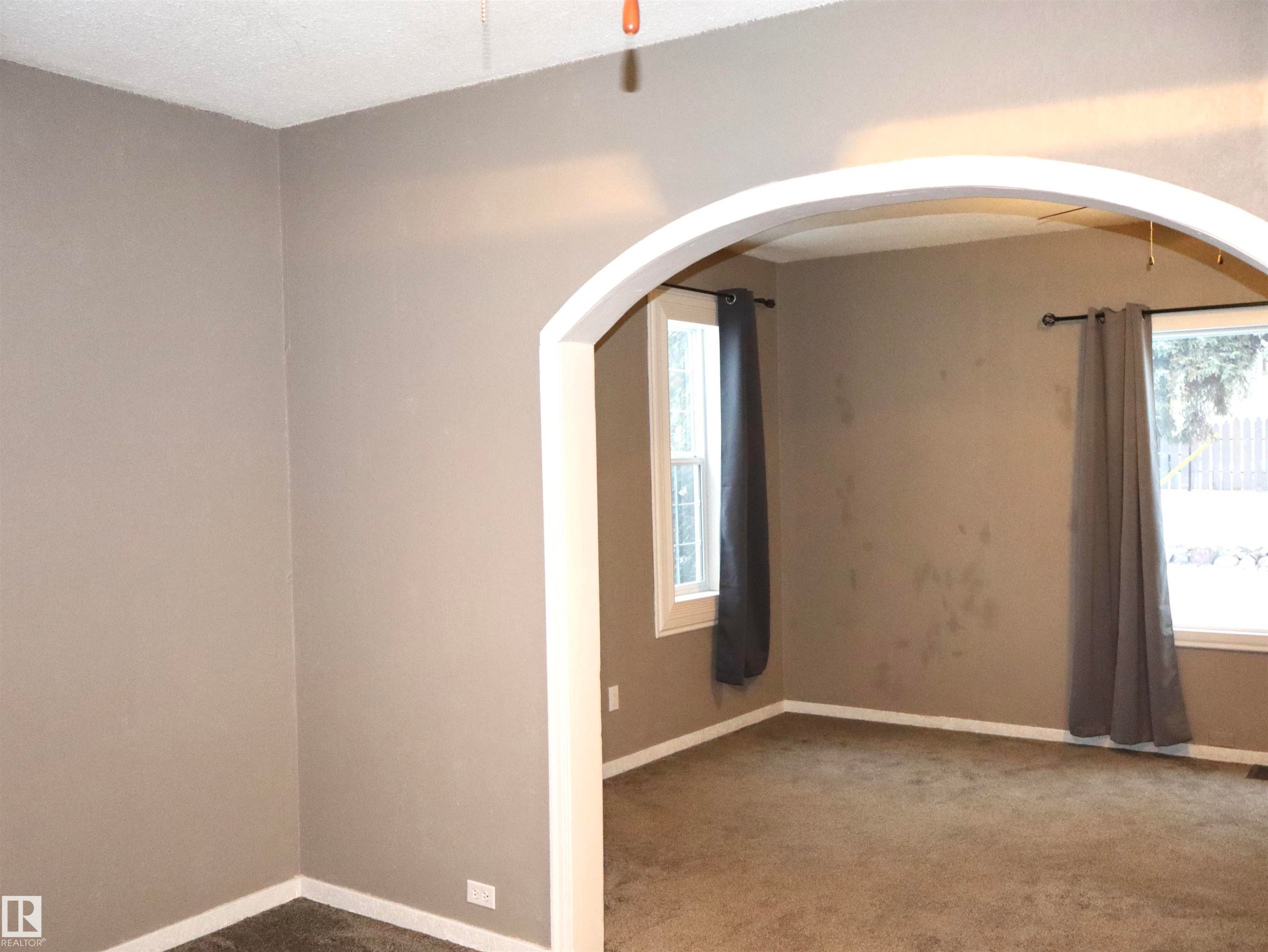 Empty room with carpet flooring and arched walkways - 4511 53 Ave, Barrhead, AB - Indoor Photo Showing Other Room