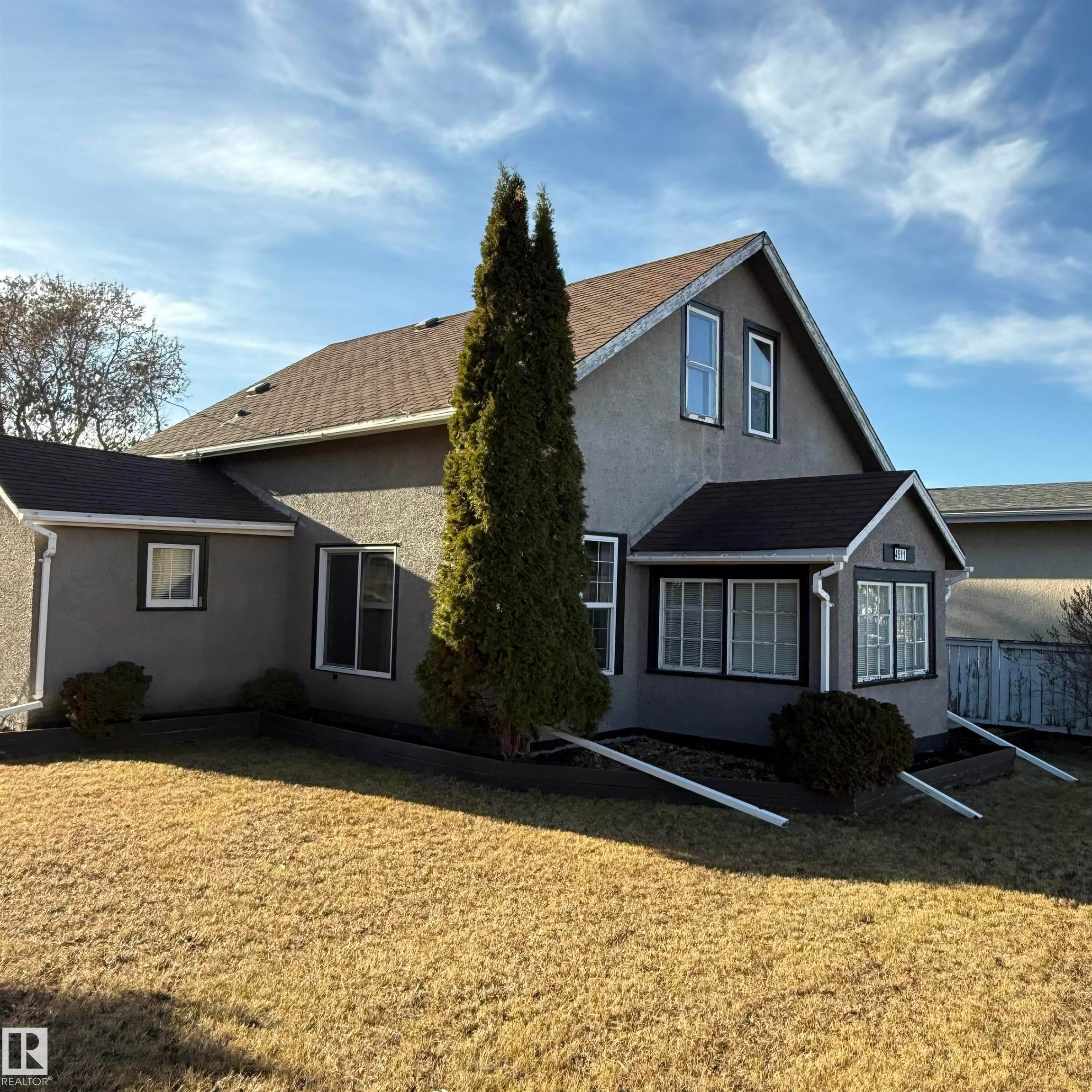 Rear view of house featuring stucco siding and a shingled roof - 4511 53 Ave, Barrhead, AB - Outdoor