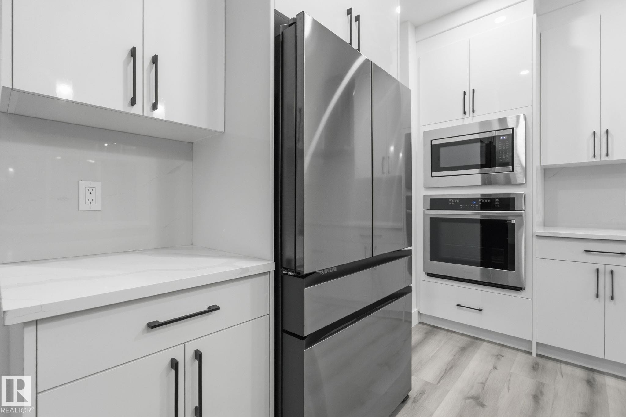 Kitchen with stainless steel appliances, white cabinetry, modern cabinets, and light wood-style floors - 2532 210 Street, Edmonton, AB - Indoor Photo Showing Kitchen