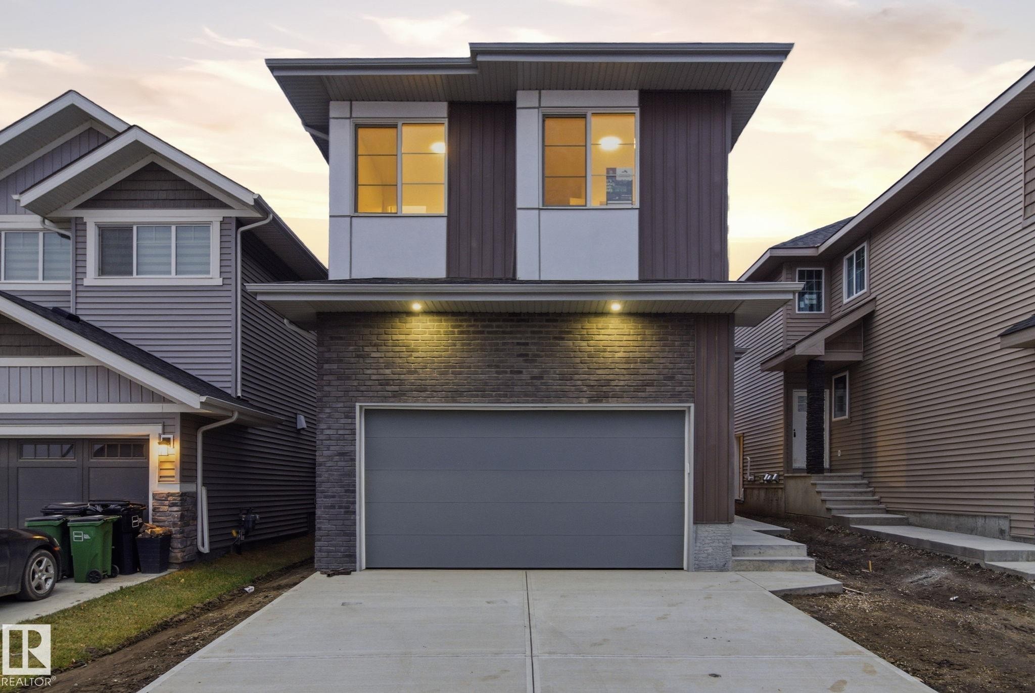 Contemporary home featuring concrete driveway, an attached garage, board and batten siding, and stone siding - 2532 210 Street, Edmonton, AB - Outdoor