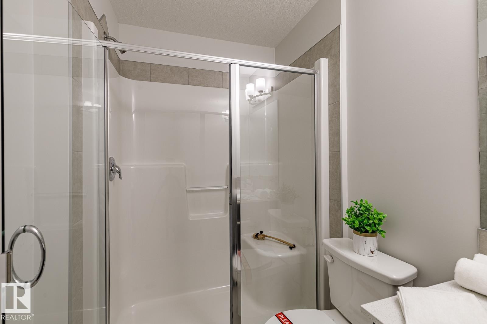 Bathroom featuring a stall shower, vanity, and a textured ceiling - 3617 Triomphe Boulevard, Beaumont, AB - Indoor Photo Showing Bathroom