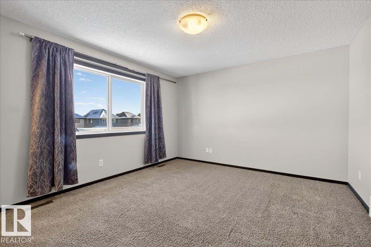 Carpeted spare room with a textured ceiling and baseboards - 3623 13 Street, Edmonton, AB - Indoor Photo Showing Other Room