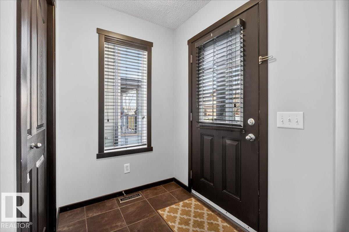Entrance foyer with plenty of natural light, a textured ceiling, and dark tile patterned floors - 3623 13 Street, Edmonton, AB - Indoor Photo Showing Other Room