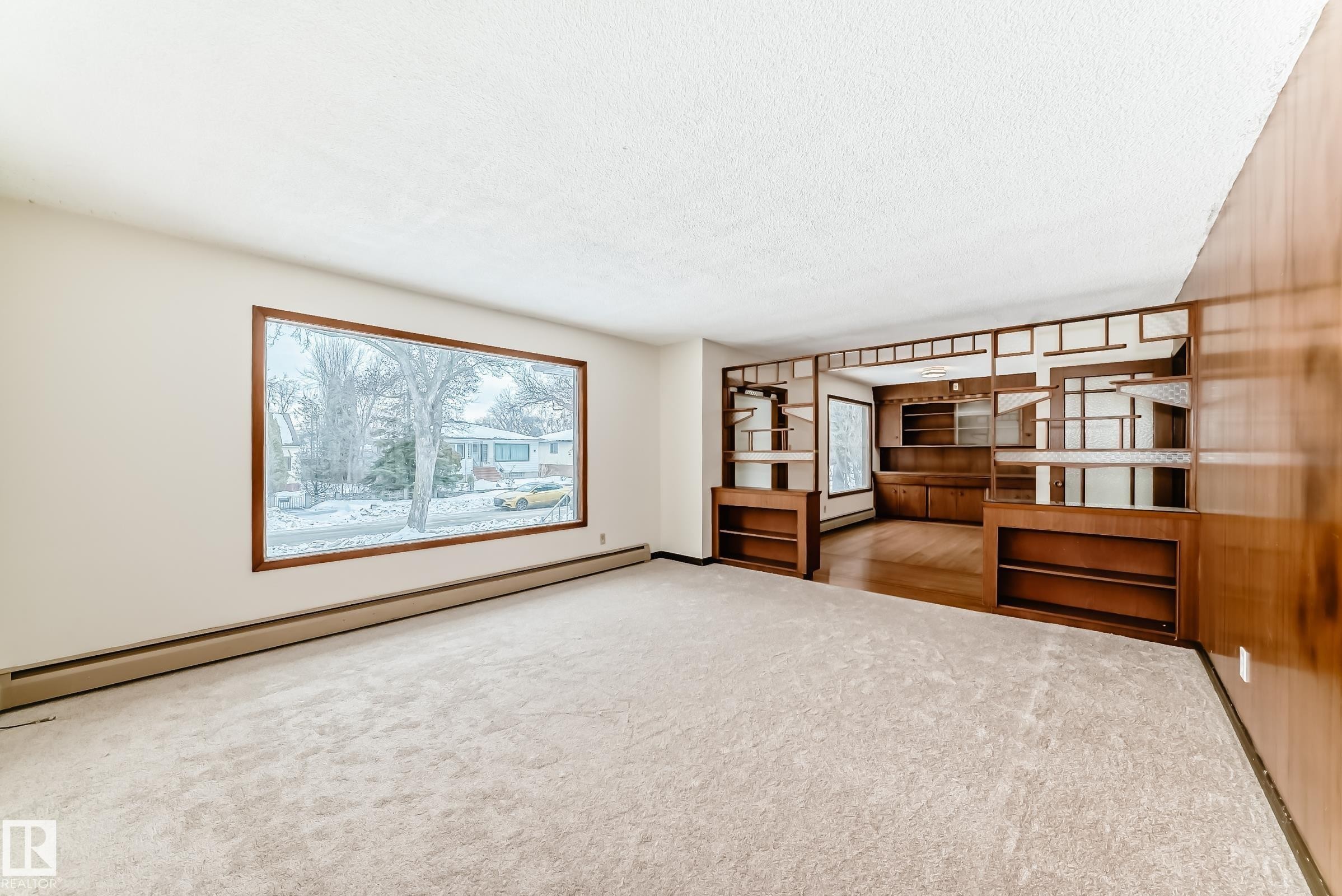 Unfurnished living room featuring a baseboard radiator, light colored carpet, and a textured ceiling - 12028 87 Street, Edmonton, AB - Indoor Photo Showing Other Room