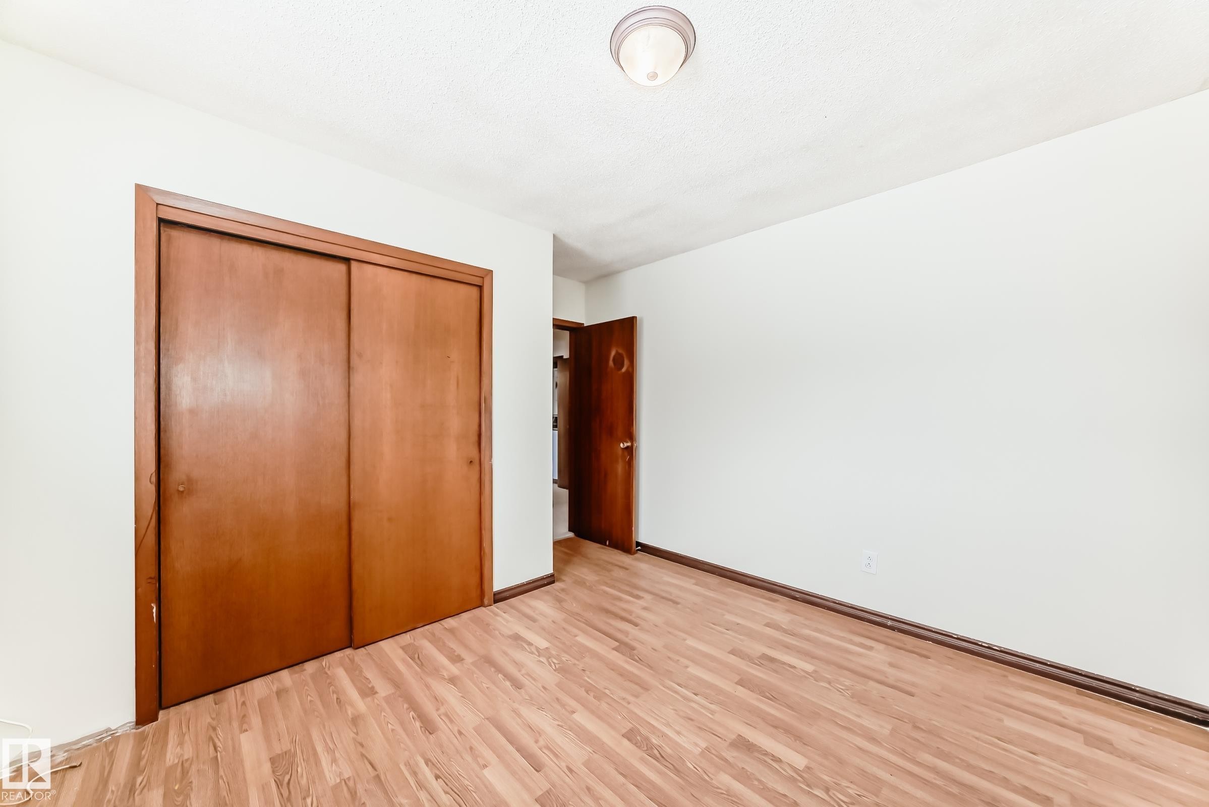 Unfurnished bedroom with light wood-type flooring and a closet - 12028 87 Street, Edmonton, AB - Indoor Photo Showing Other Room