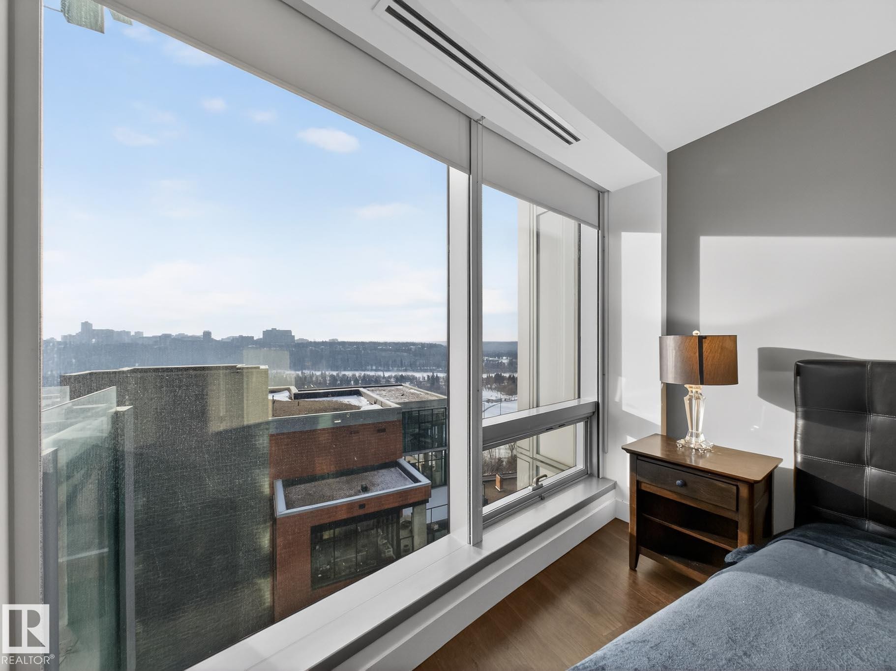 Bedroom with dark wood-type flooring and a view of city - #902 11969 Jasper Av Nw, Edmonton, AB - Indoor