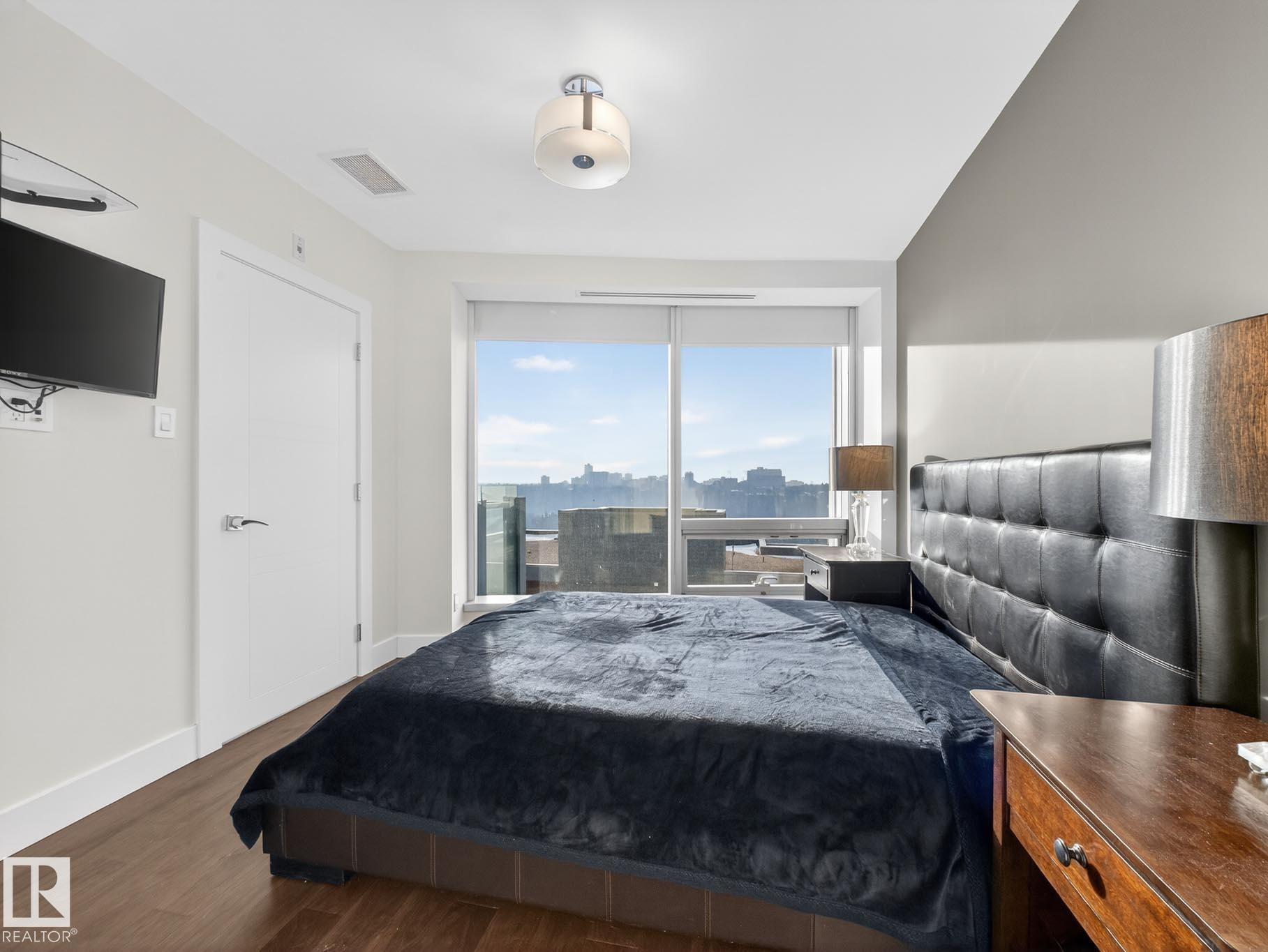 Bedroom featuring wood finished floors and access to exterior - #902 11969 Jasper Av Nw, Edmonton, AB - Indoor Photo Showing Bedroom