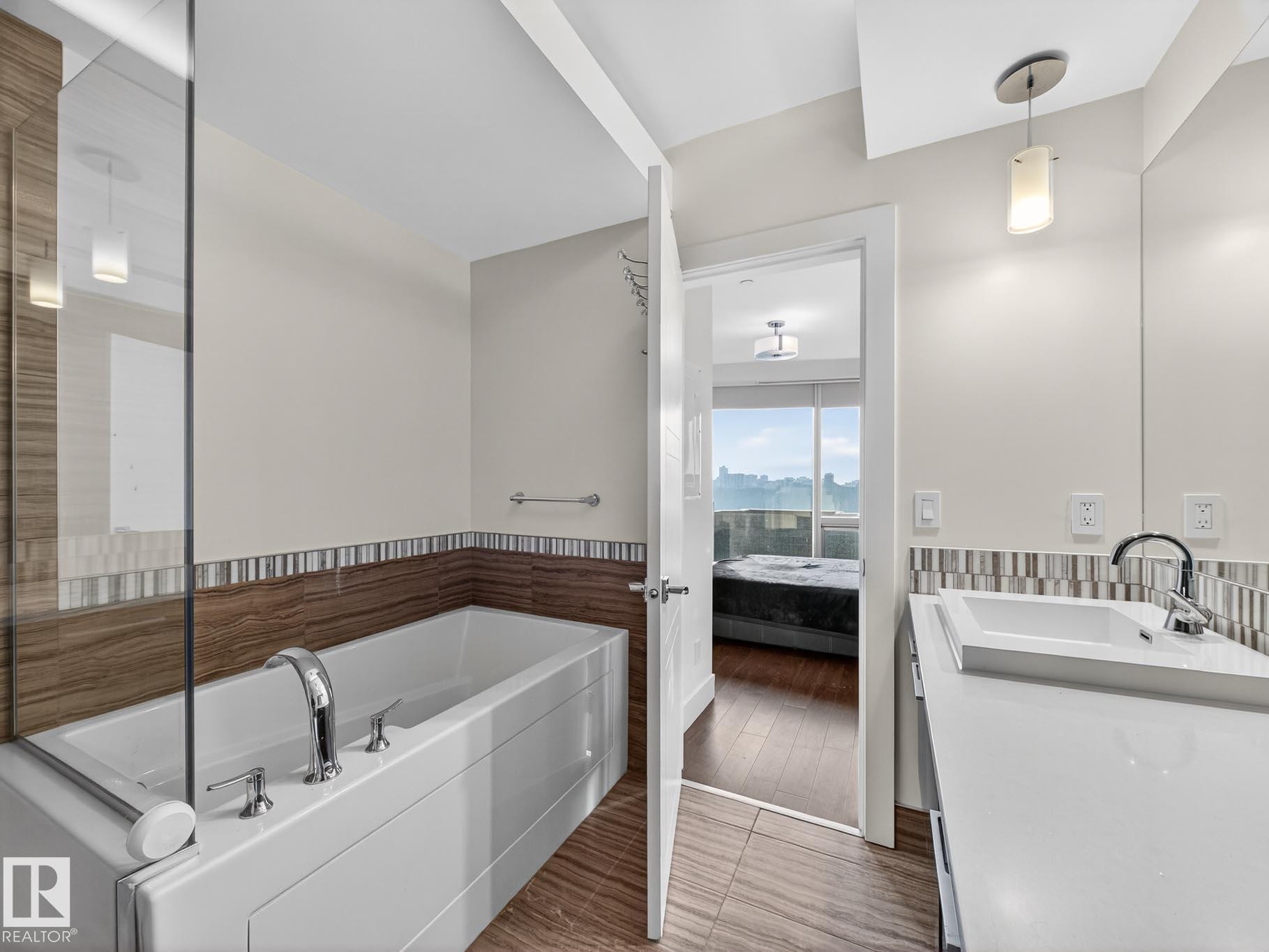 Ensuite bathroom featuring a garden tub, vanity, and a wainscoted wall - #902 11969 Jasper Av Nw, Edmonton, AB - Indoor Photo Showing Bathroom