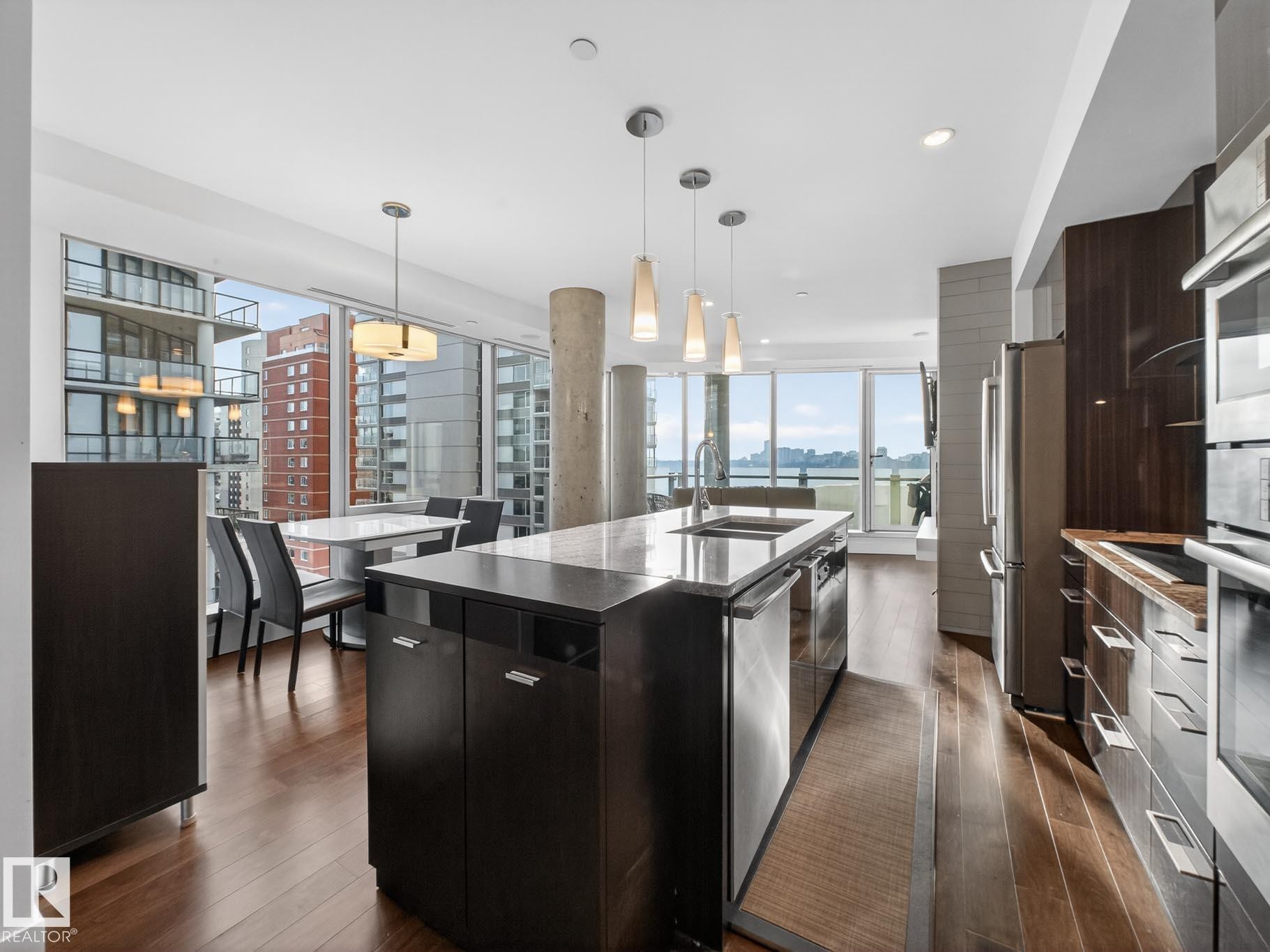 Kitchen featuring modern cabinets, pendant lighting, a large island with sink, dark wood finished floors, and stainless steel appliances - #902 11969 Jasper Av Nw, Edmonton, AB - Indoor Photo Showing Kitchen With Stainless Steel Kitchen With Upgraded Kitchen