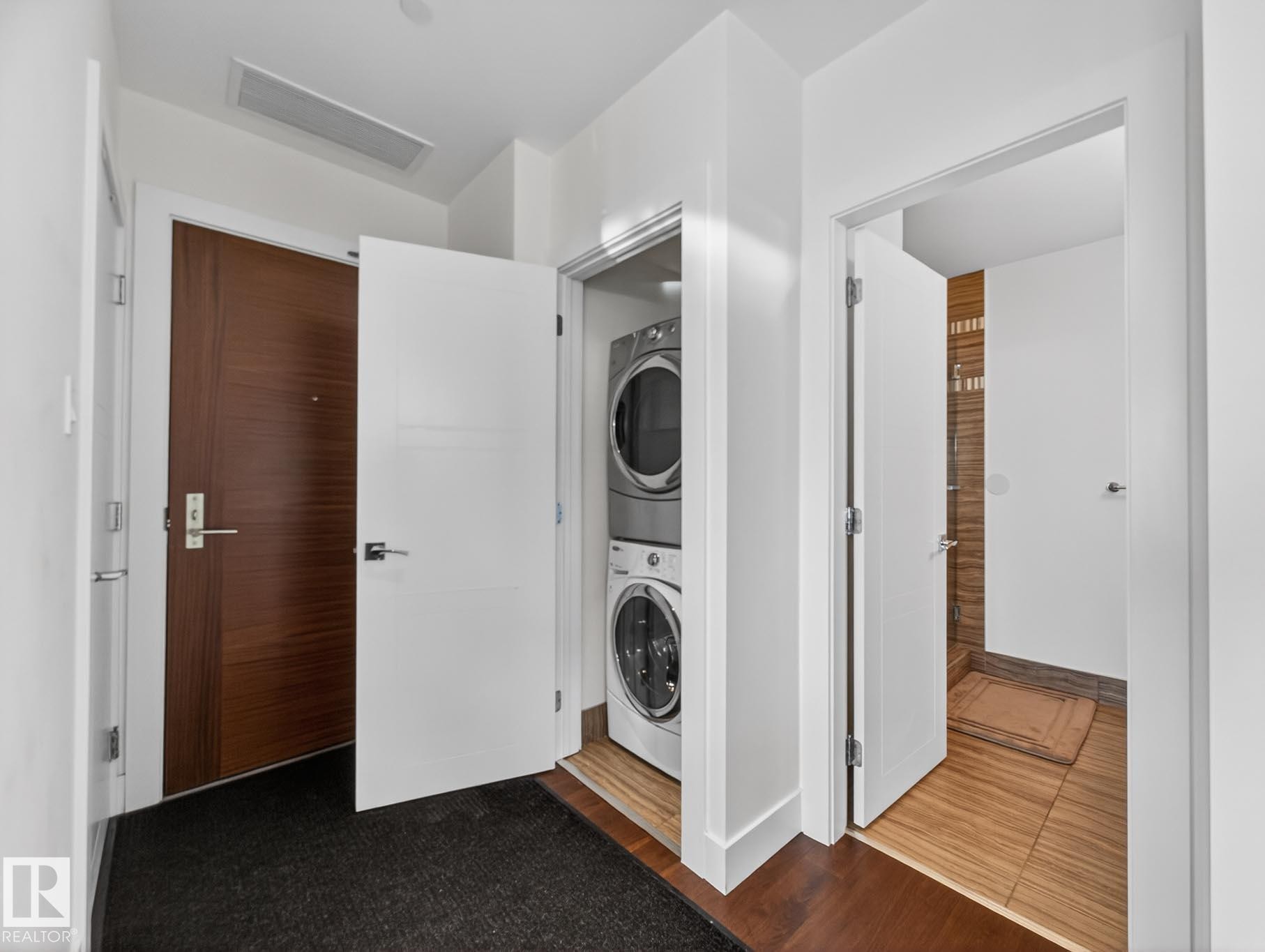 Washroom with stacked washer / drying machine and dark wood-type flooring - #902 11969 Jasper Av Nw, Edmonton, AB - Indoor Photo Showing Laundry Room