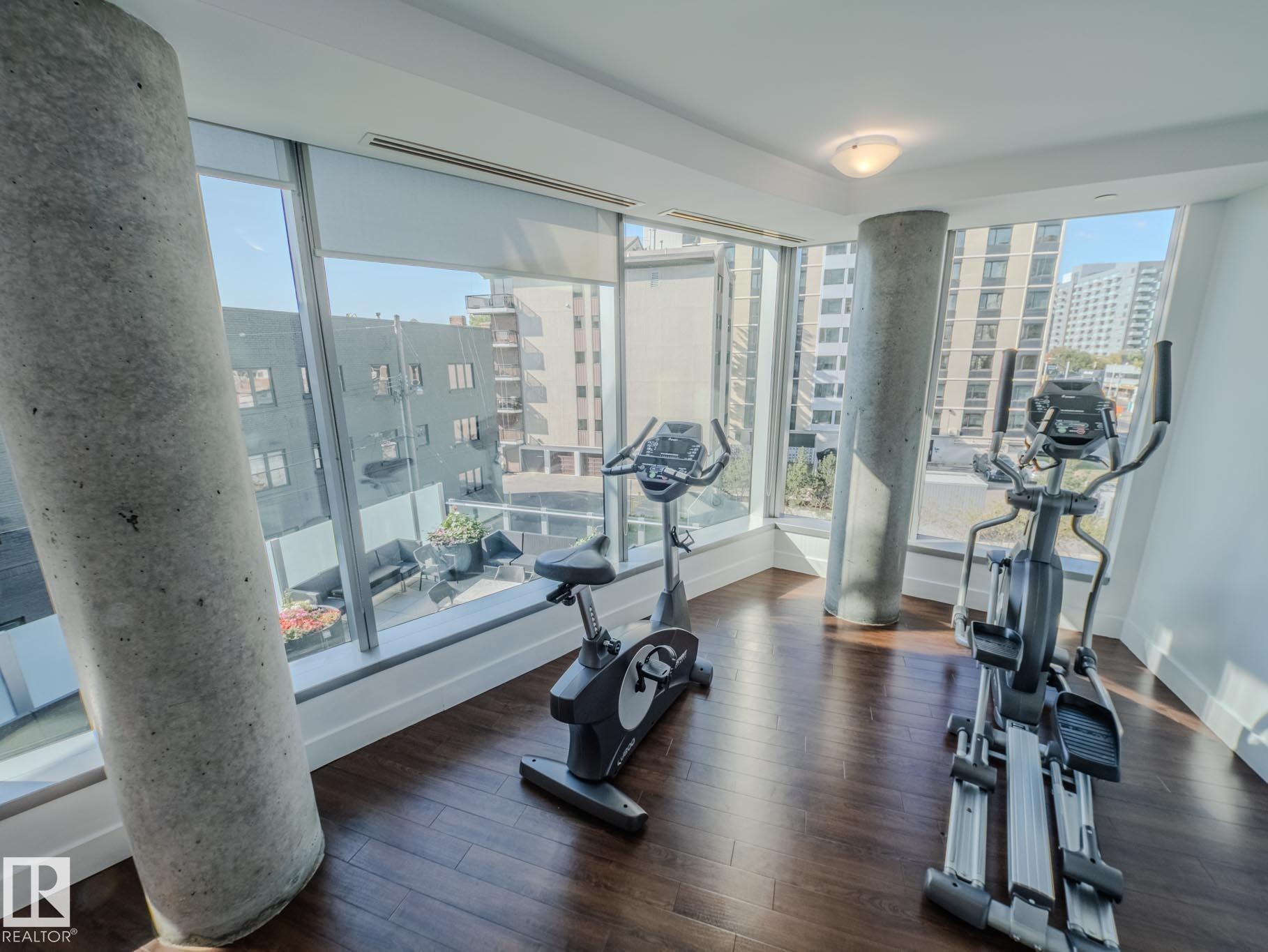 Exercise room with dark wood finished floors, plenty of natural light, and a view of city - #902 11969 Jasper Av Nw, Edmonton, AB - Indoor Photo Showing Gym Room