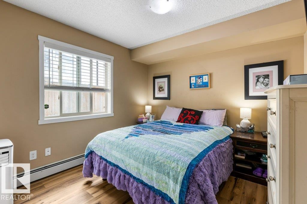 Bedroom with a baseboard radiator, a textured ceiling, and wood finished floors - 107 25 Element Dr, St. Albert, AB - Indoor Photo Showing Bedroom