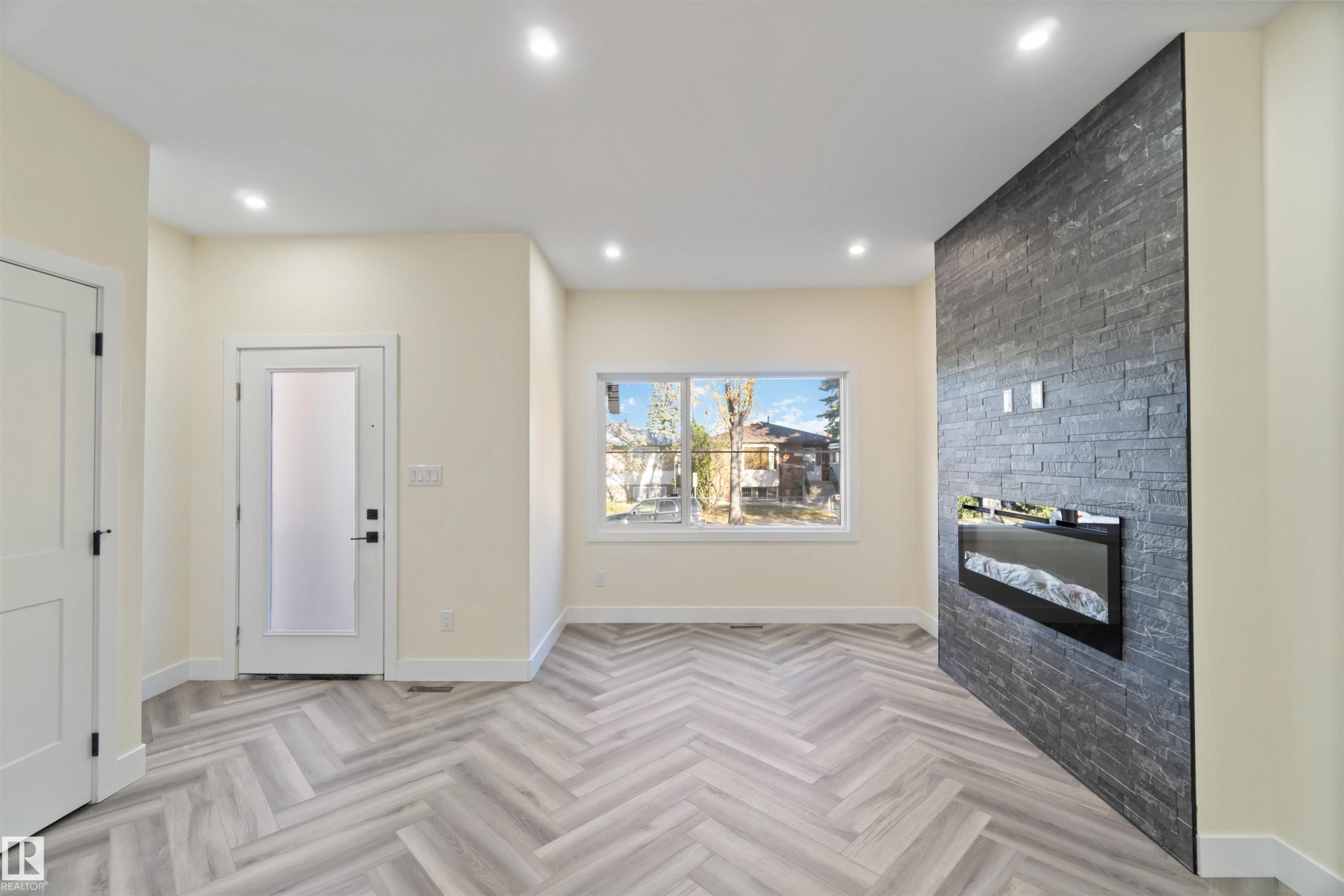 Entrance foyer with a fireplace, parquet flooring, and recessed lighting - 8319 81Ave, Edmonton, AB - Indoor Photo Showing Other Room With Fireplace