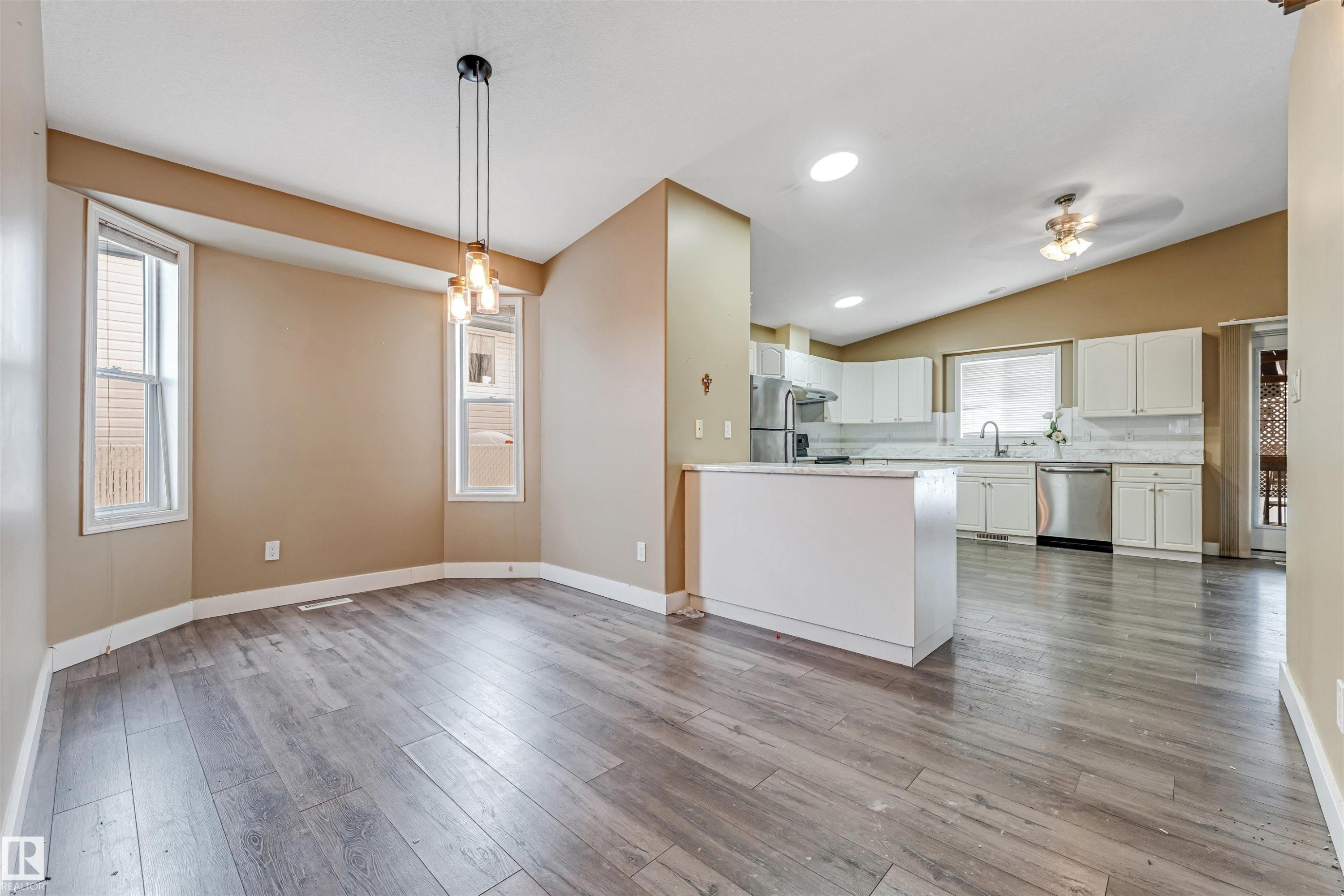 Kitchen with white cabinetry, pendant lighting, appliances with stainless steel finishes, light wood-style flooring, and vaulted ceiling - 6741 162A Avenue, Edmonton, AB - Indoor Photo Showing Kitchen
