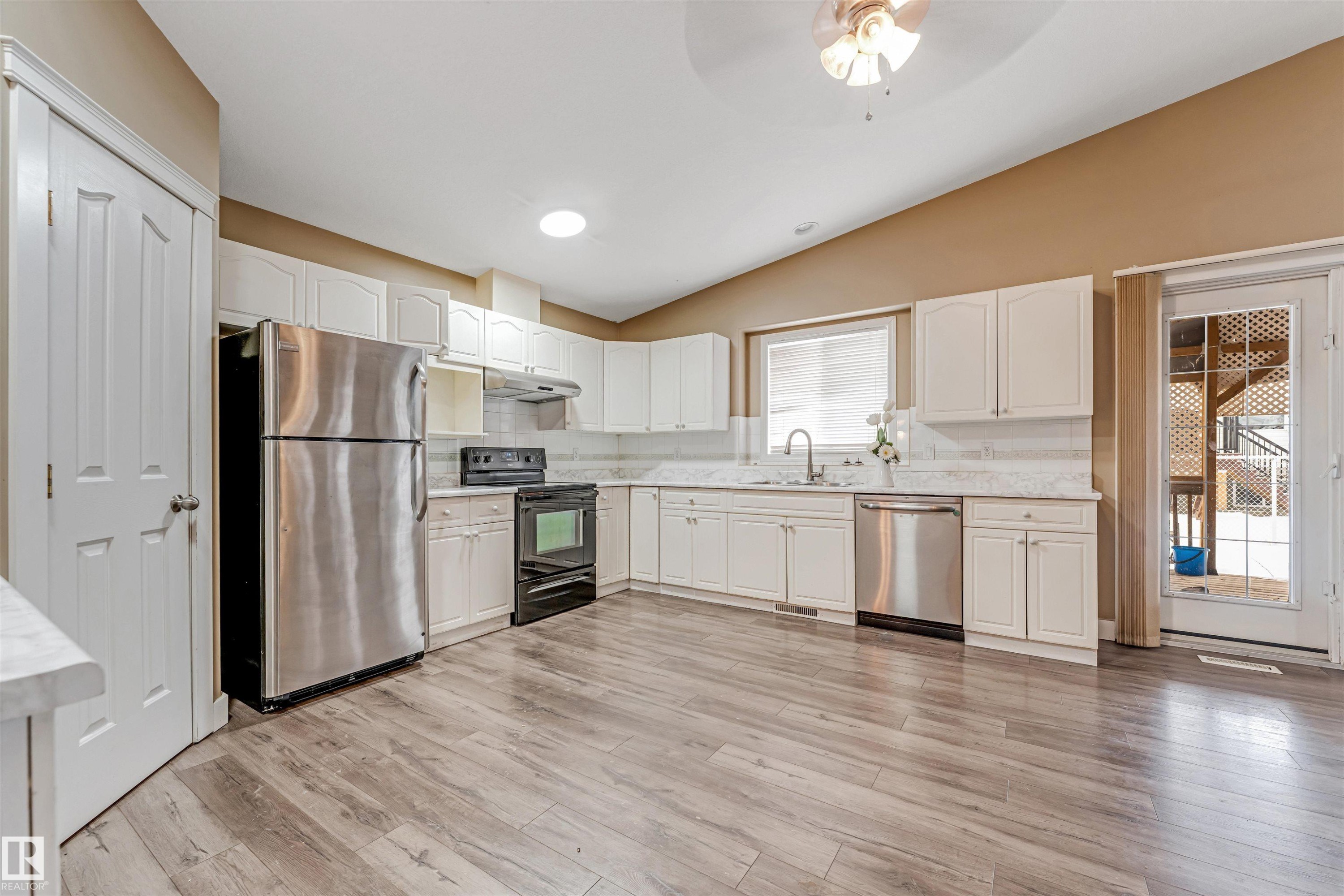 Kitchen with stainless steel appliances, white cabinets, lofted ceiling, light wood-style floors, and ceiling fan - 6741 162A Avenue, Edmonton, AB - Indoor Photo Showing Kitchen