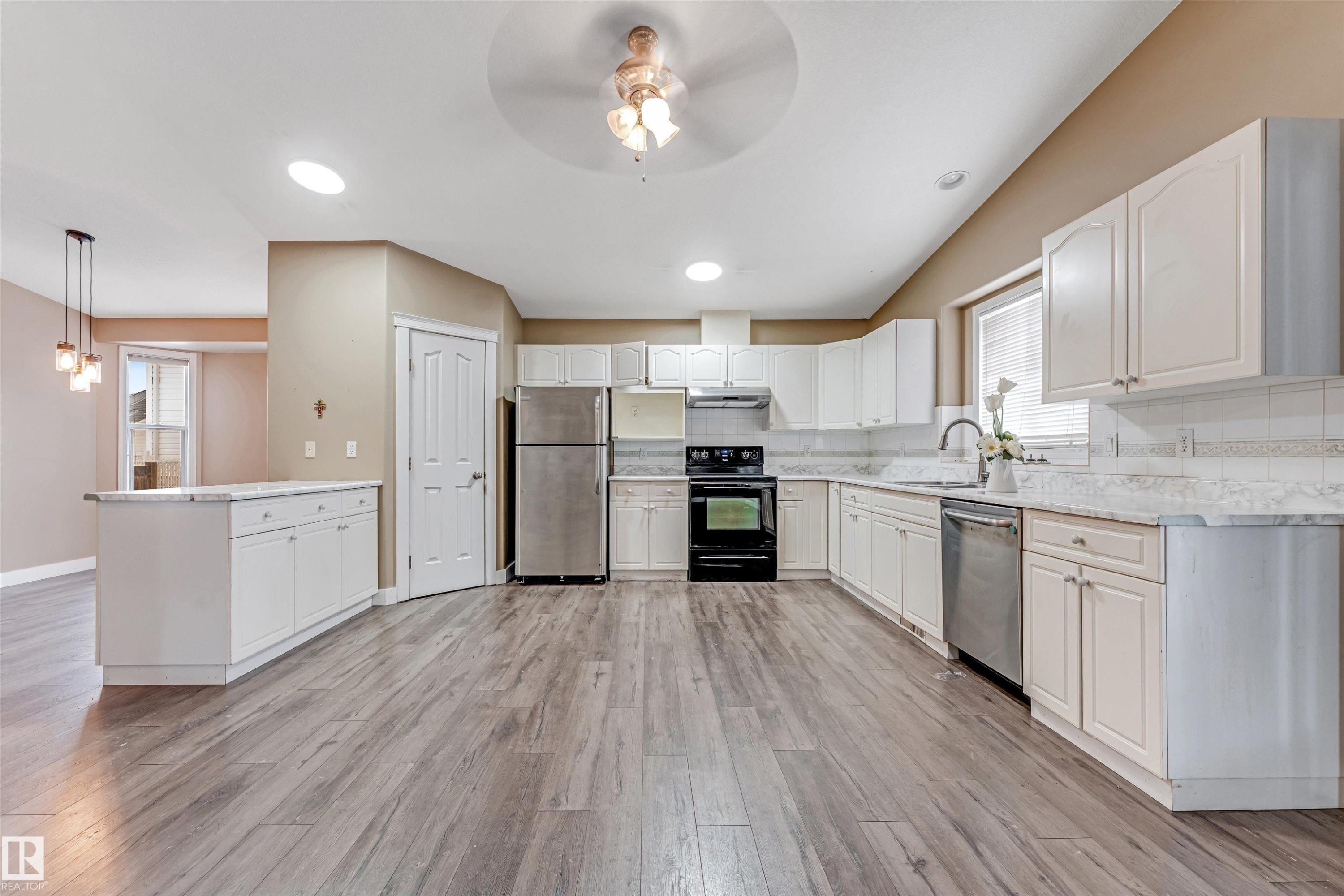Kitchen with appliances with stainless steel finishes, decorative backsplash, white cabinetry, a peninsula, and a ceiling fan - 6741 162A Avenue, Edmonton, AB - Indoor Photo Showing Kitchen