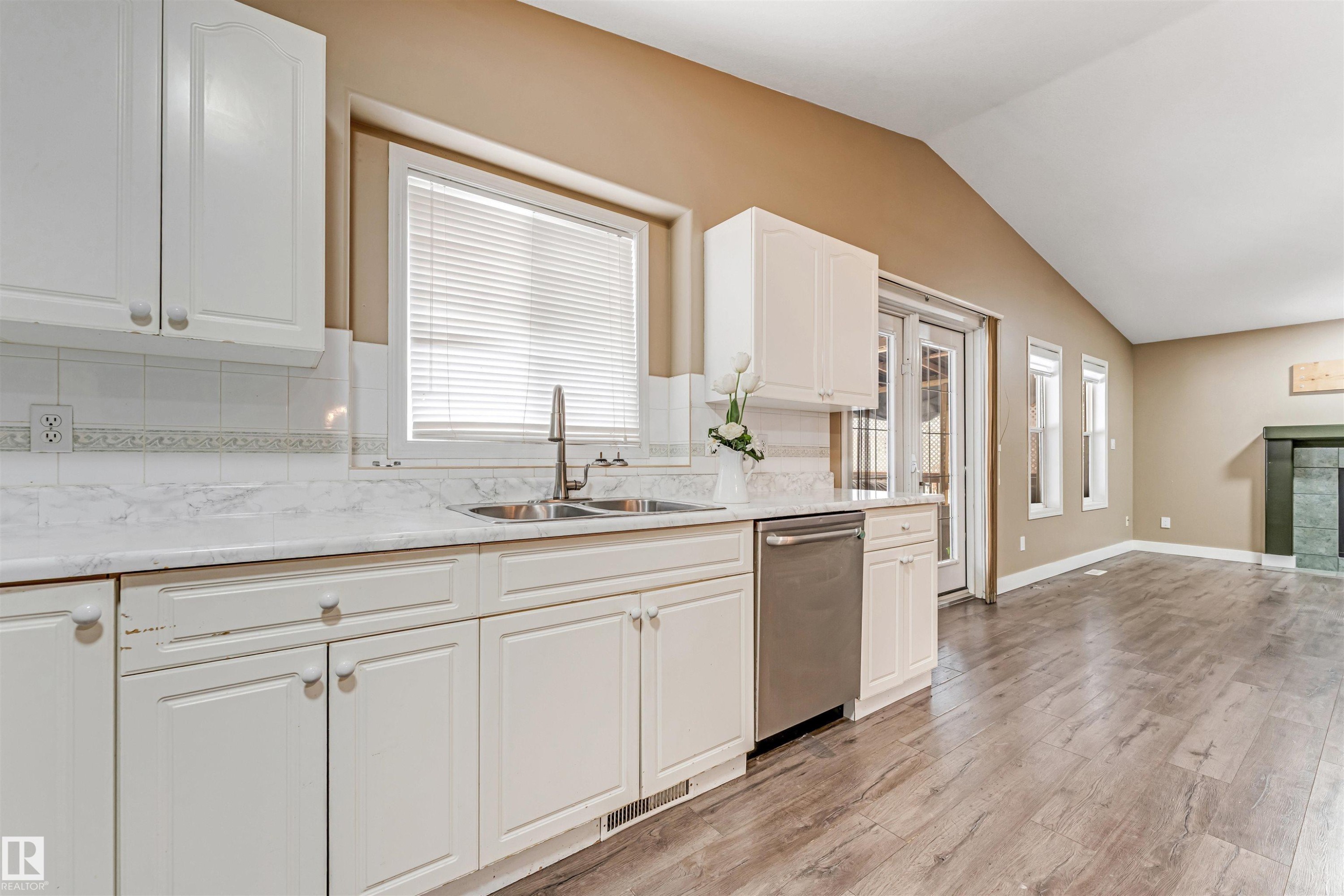 Kitchen with light wood-style floors, dishwasher, decorative backsplash, white cabinetry, and lofted ceiling - 6741 162A Avenue, Edmonton, AB - Indoor Photo Showing Kitchen With Double Sink