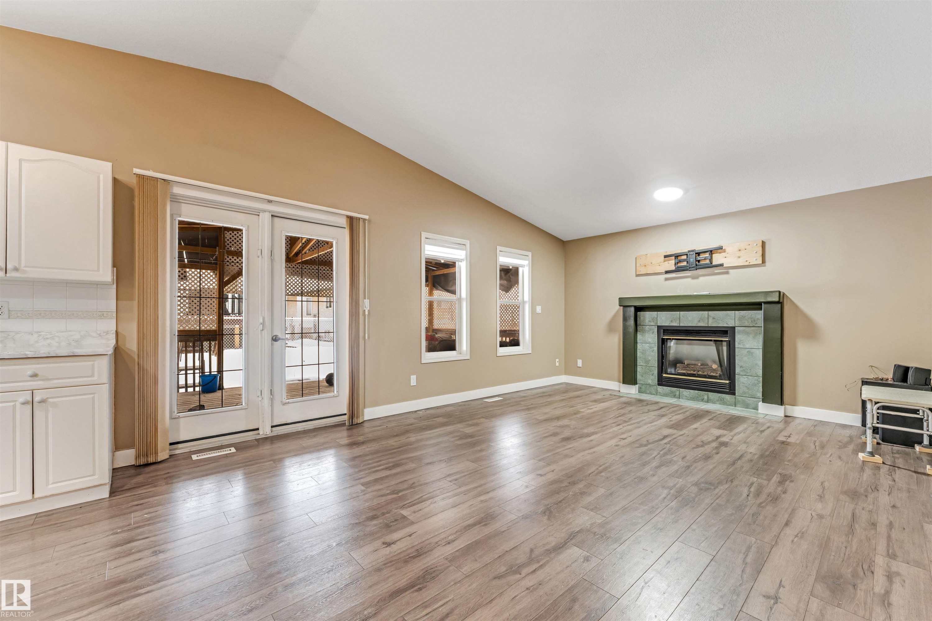 Unfurnished living room with french doors, vaulted ceiling, light wood-type flooring, and a fireplace - 6741 162A Avenue, Edmonton, AB - Indoor Photo Showing Living Room With Fireplace