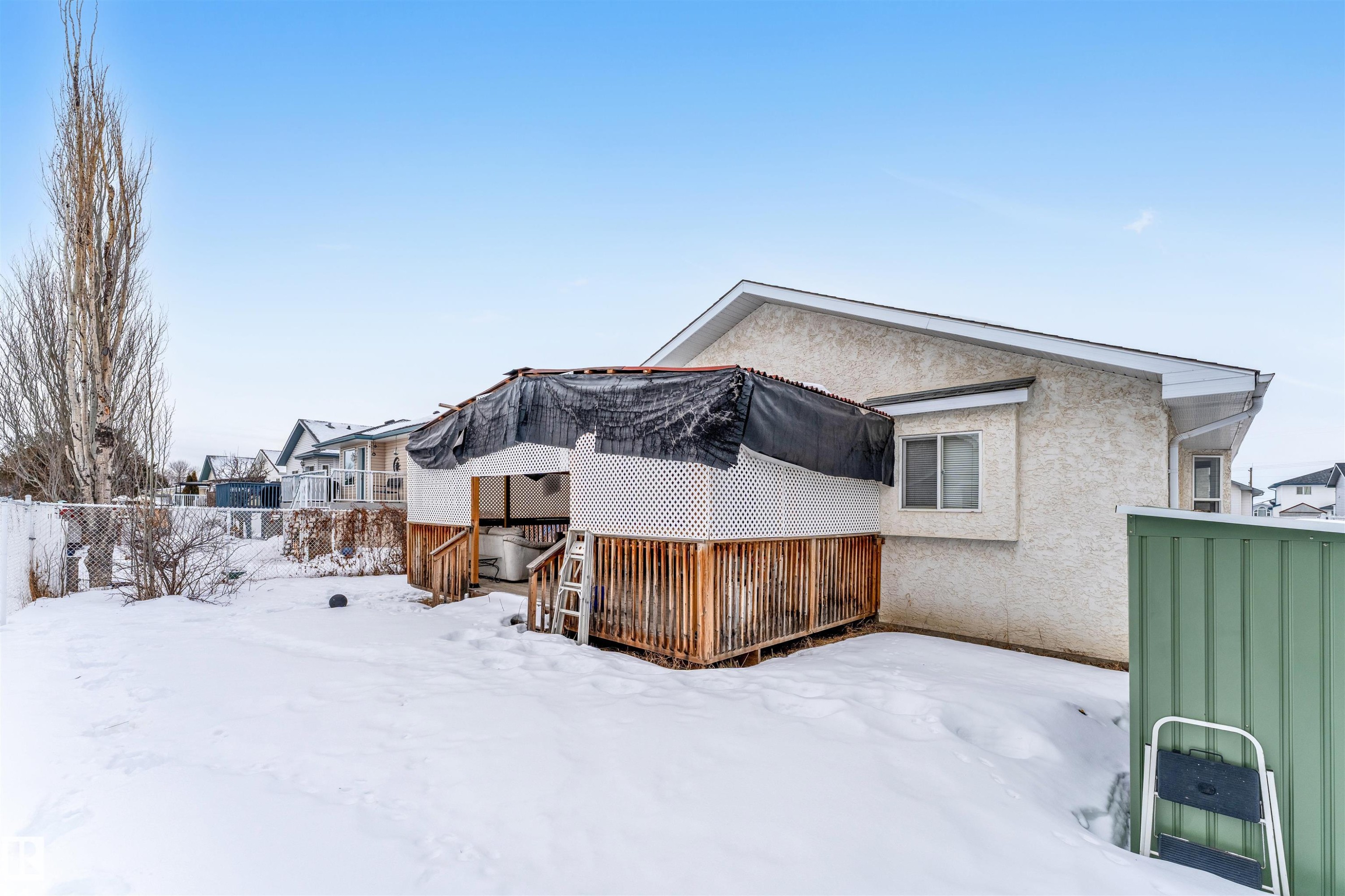 Snow covered property with a wooden deck, stucco siding, and a residential view - 6741 162A Avenue, Edmonton, AB - Outdoor With Exterior