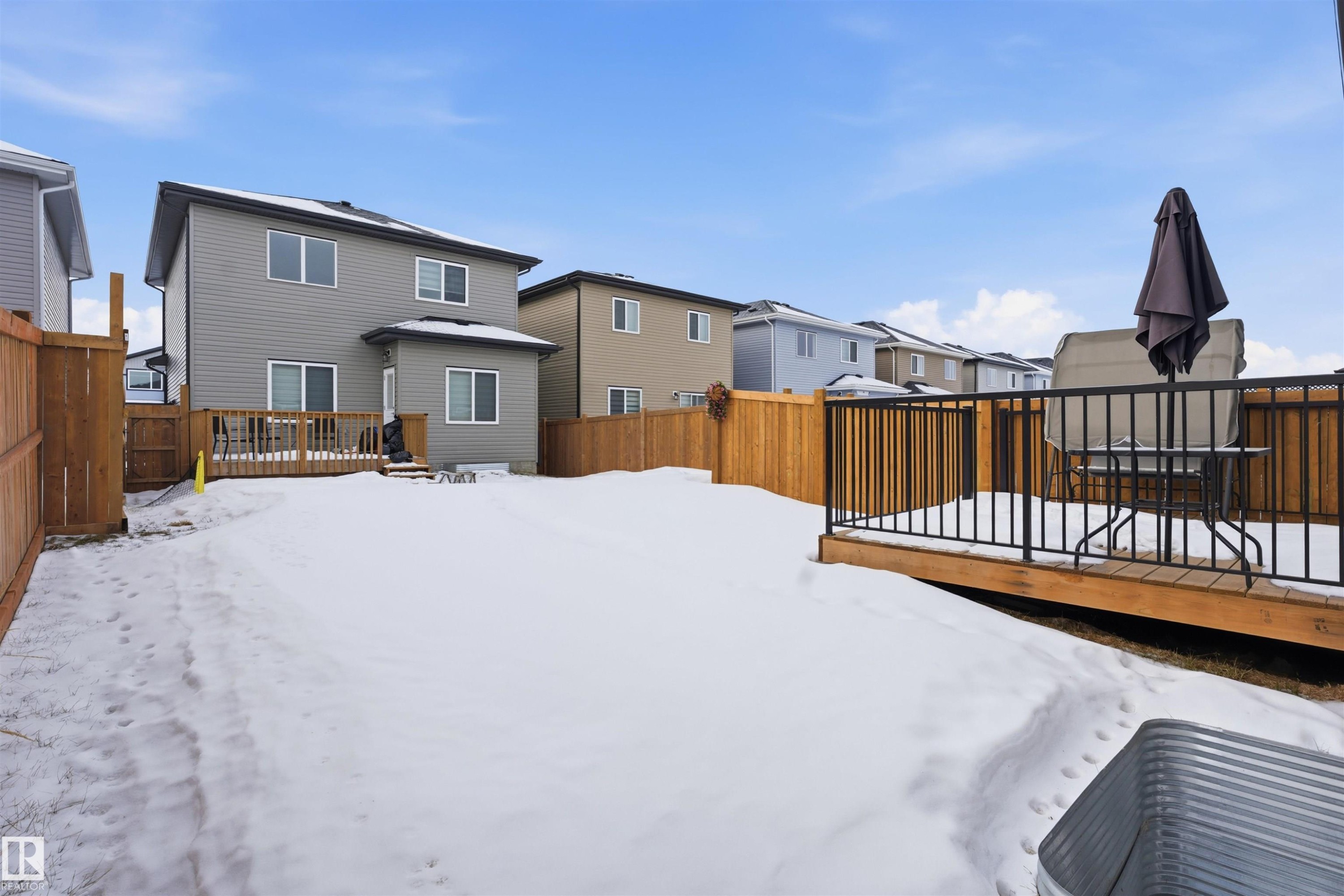 Snow covered property with a deck, a fenced backyard, and a residential view - 452 Roberts Crescent, Leduc, AB - Outdoor With Exterior