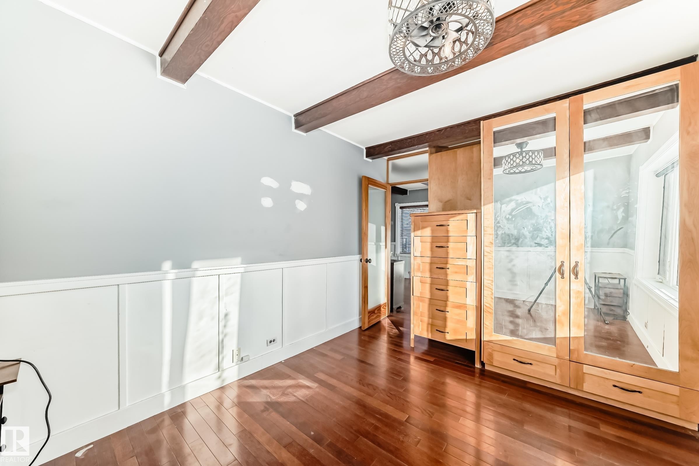Empty room with french doors, hardwood / wood-style floors, beam ceiling, a decorative wall, and wainscoting - 10115 104, Westlock, AB - Indoor Photo Showing Other Room