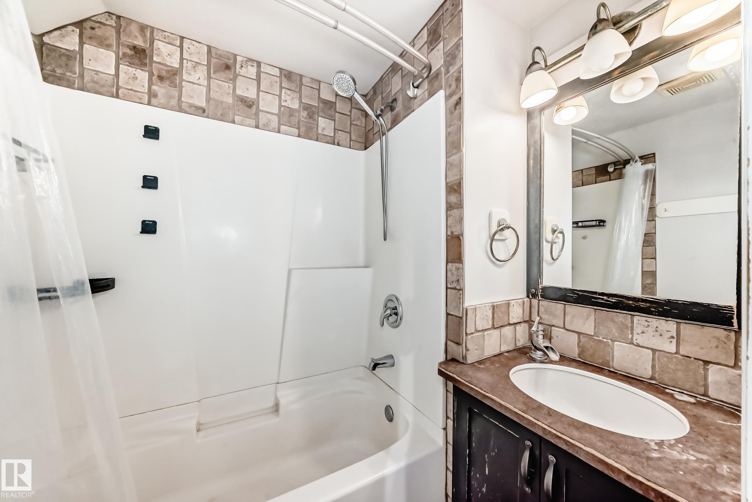 Full bathroom with decorative backsplash, shower / bath combo with shower curtain, and vanity - 10115 104, Westlock, AB - Indoor Photo Showing Bathroom